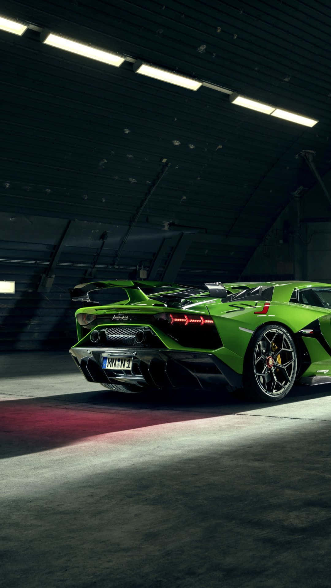 跑車 桌布 壁紙 — 一輛鮮綠色藍寶堅尼 Aventador SVJ 停放在昏暗的工業車庫中，帶有紅色地板照明。
