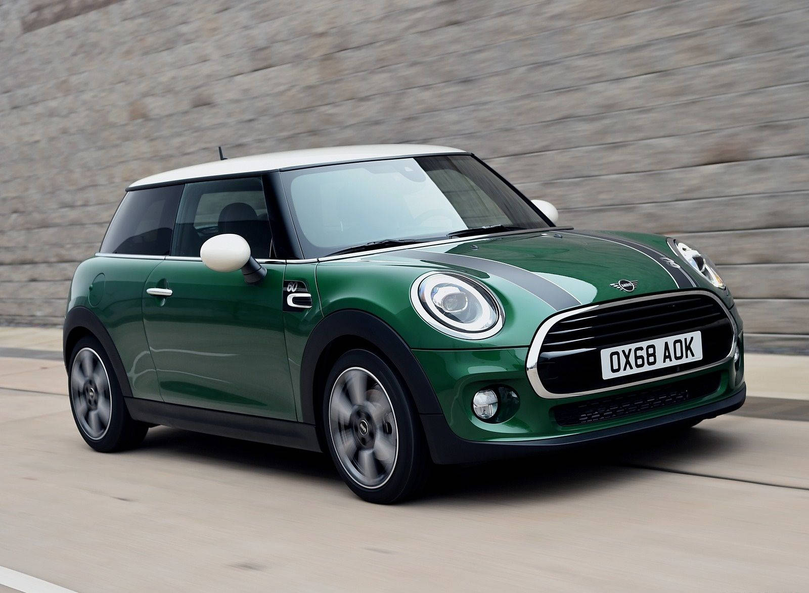 Mini Cooper 桌布 壁紙 — 一輛鮮綠色車頂白色的Mini Cooper在陽光明媚的道路上飛馳經過石牆。