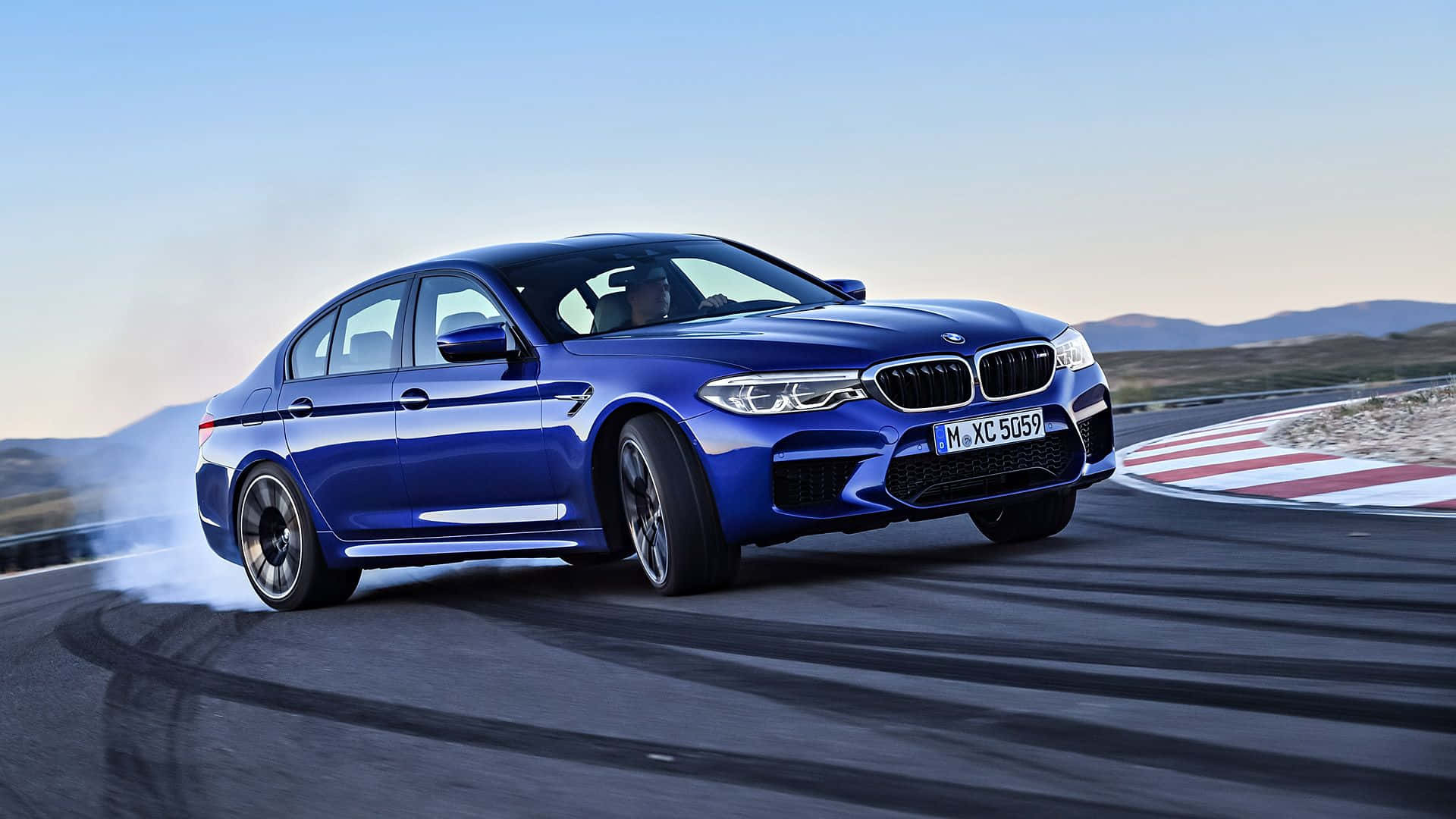 Bmw M5 桌布 壁紙 — 一輛鮮藍色BMW M5在賽道彎道飄移，在晴朗天空下揚起煙霧。