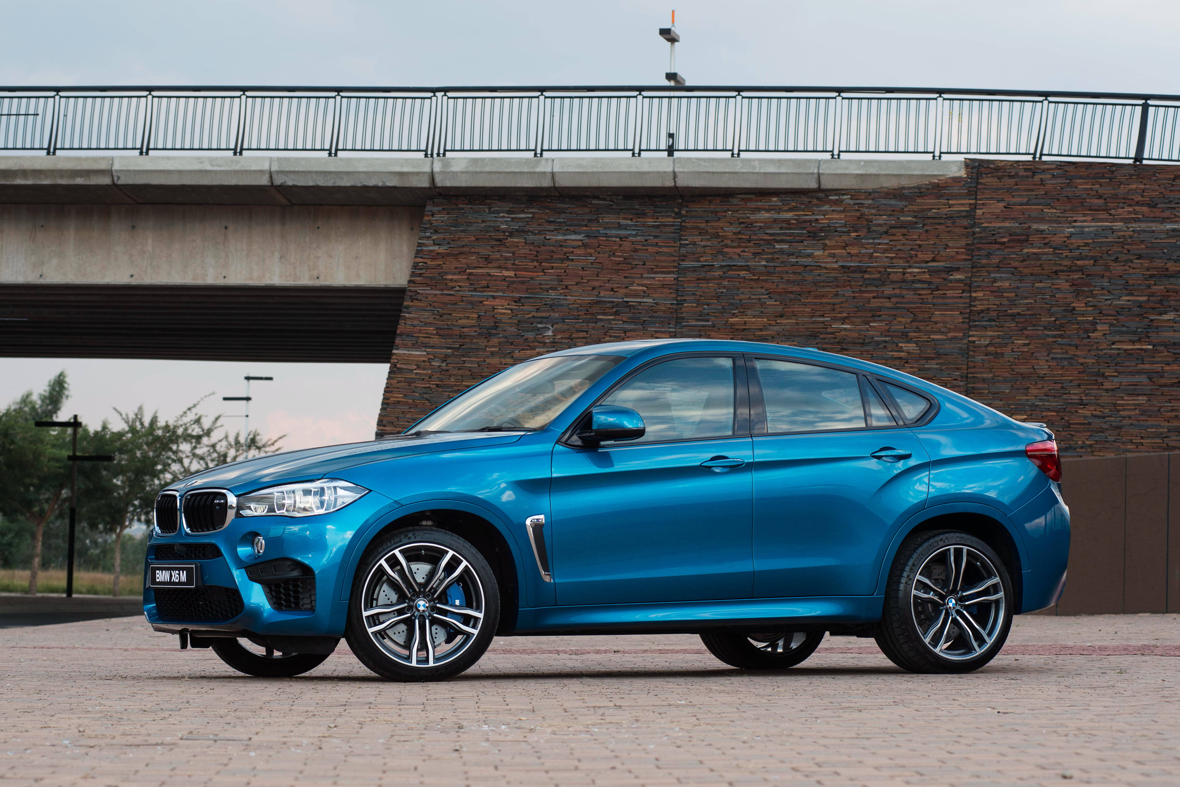 m 桌布 壁紙 — 一輛鮮藍色BMW X6M SUV停放在混凝土橋下，背景為石牆。