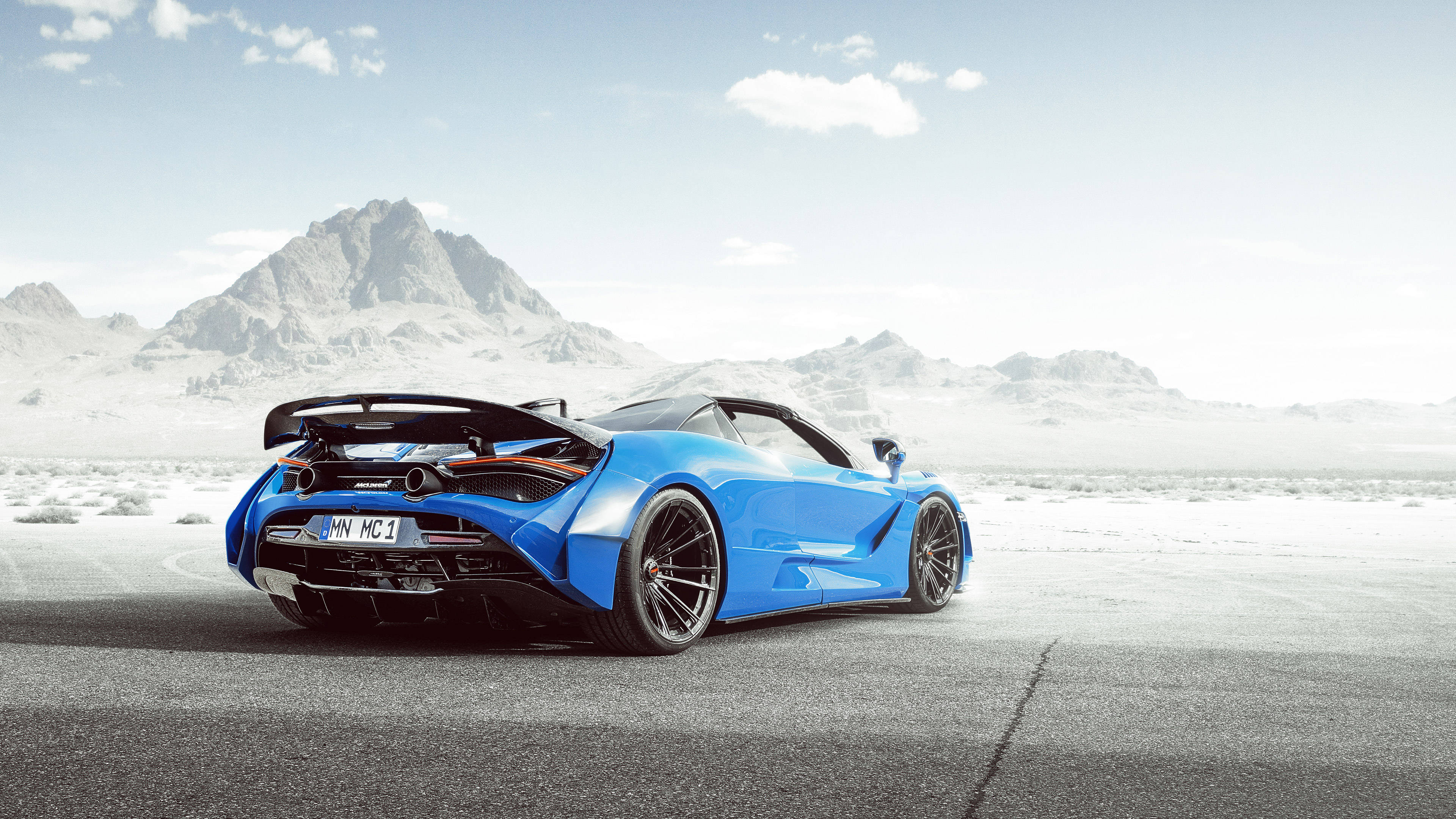 mclaren 720s 4K 桌布 壁紙 — 一輛鮮藍色McLaren跑車停泊在沙漠公路上，背景是晴朗天空下的雪山。