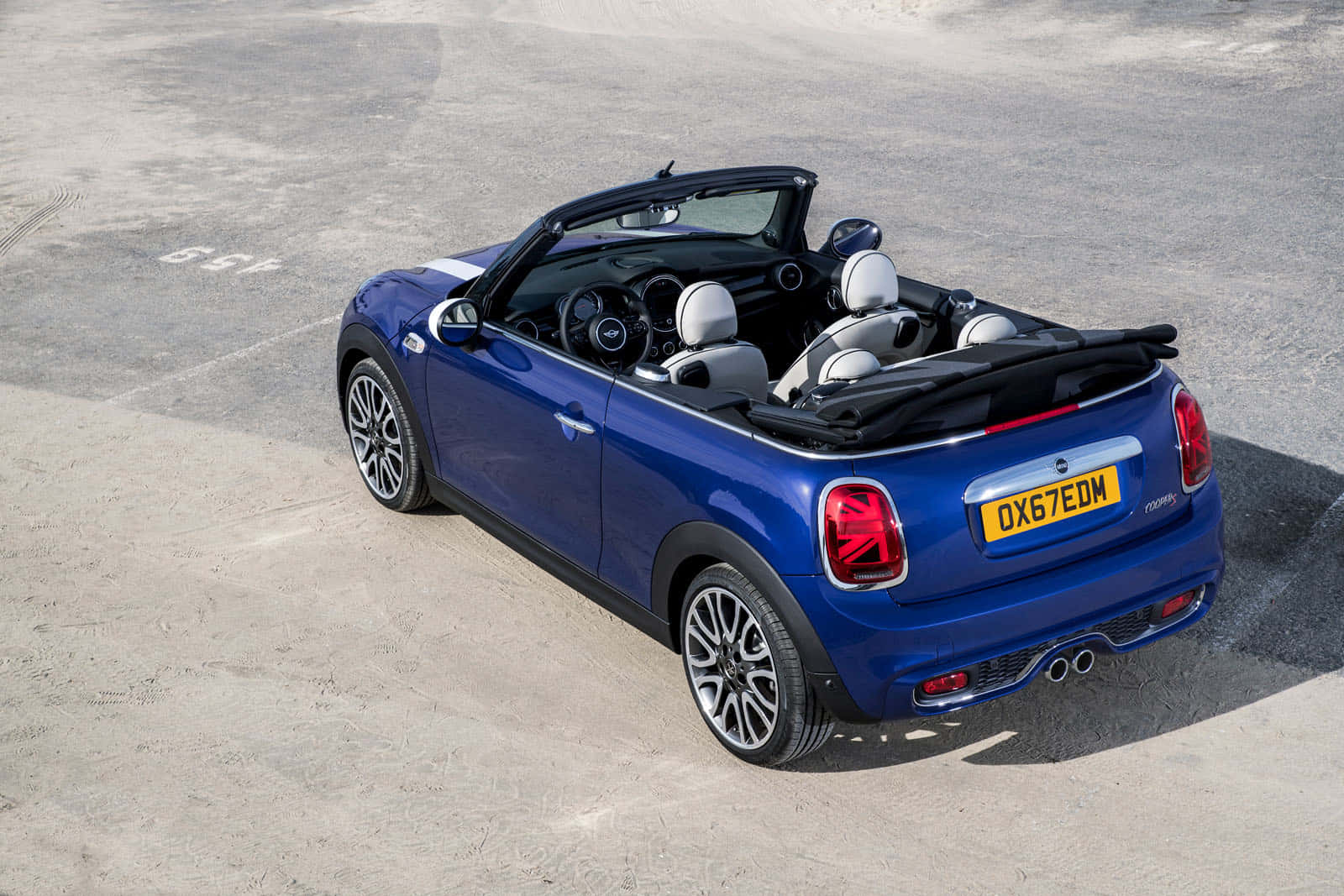 Mini Cooper Convertible 桌布 壁紙 — 一輛鮮藍色MINI敞篷車停放在陽光普照的混凝土場地上，車頂敞開露出白色皮革座椅。