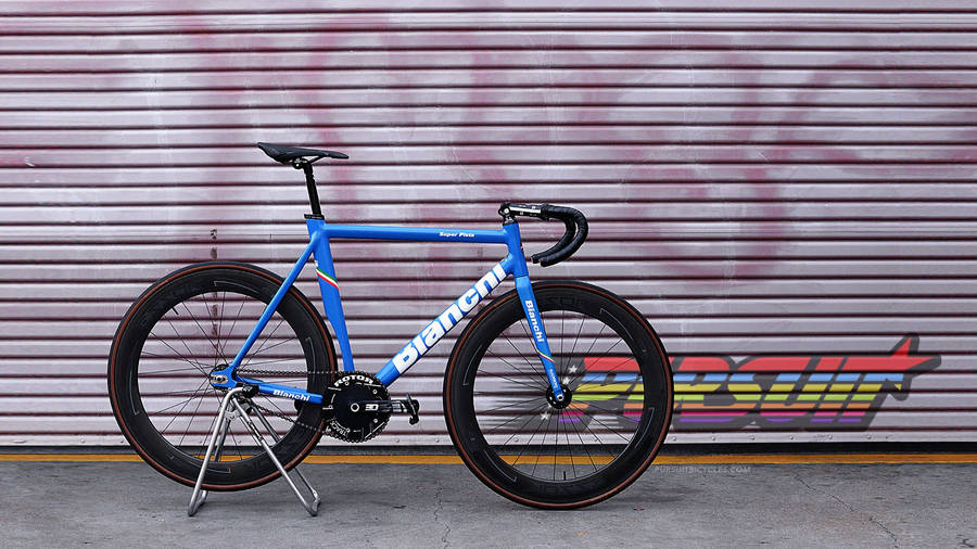 桌布 壁紙 — 一輛鮮藍色的Bianchi公路自行車用腳架撐著，停靠在一個佈滿塗鴉、帶有醒目彩虹字母的金屬捲簾前。