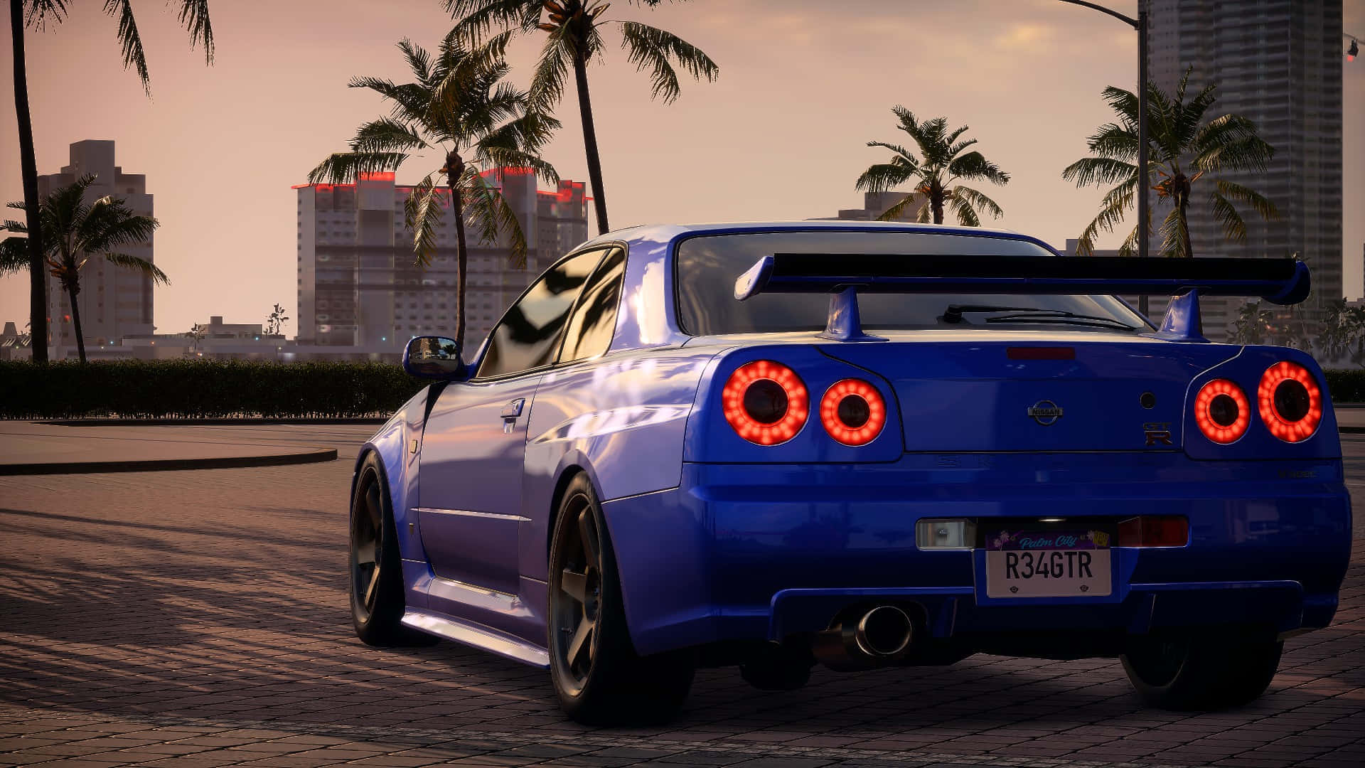電玩遊戲 桌布 壁紙 — 一輛鮮藍色的日產R34 GT-R，帶有發光的紅色尾燈，停泊在日落時分棕櫚樹成行的城市街道上。