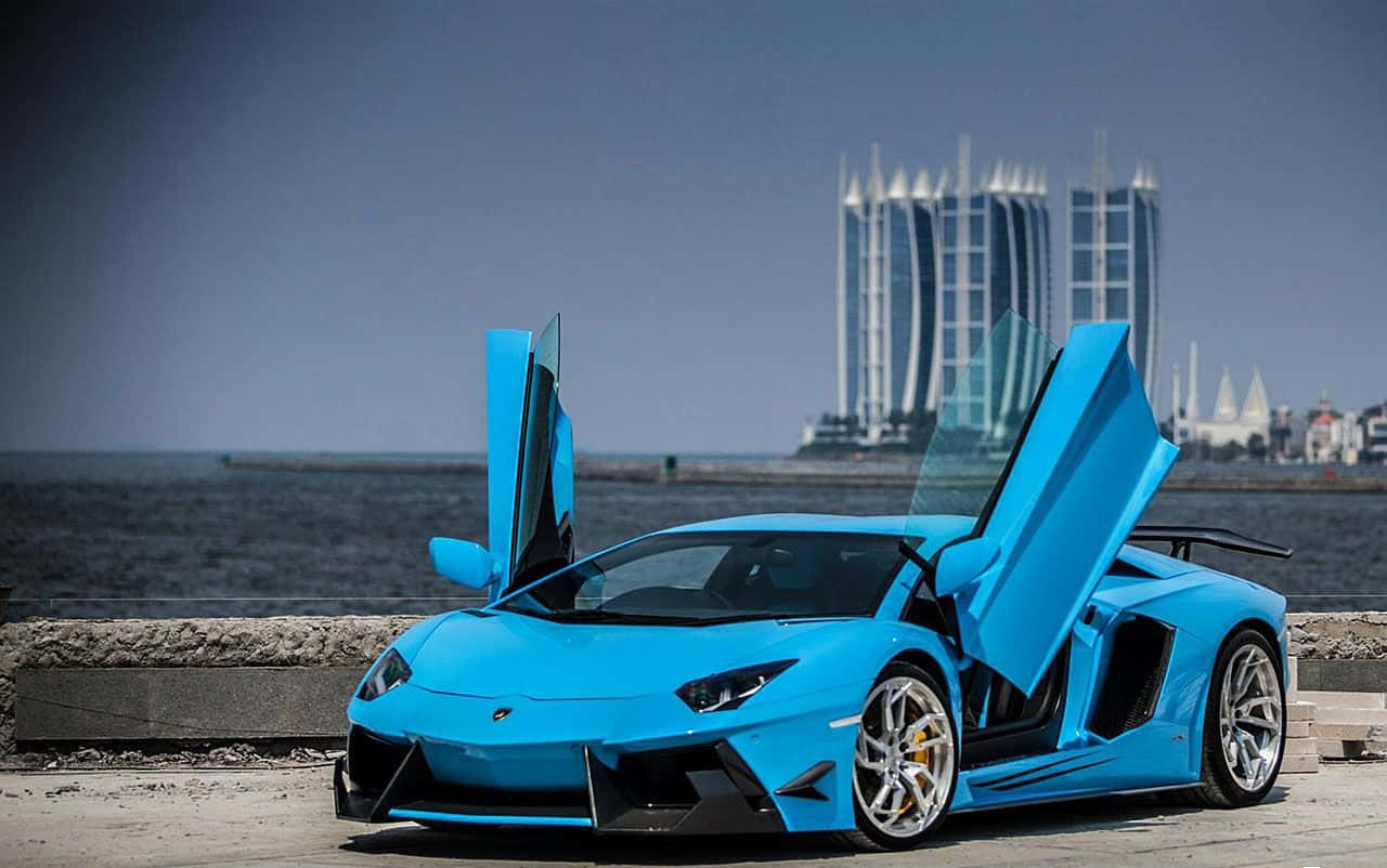 跑車 桌布 壁紙 — 一輛鮮藍色藍寶堅尼Aventador打開鷗翼車門，停在海濱長廊上，背景是現代摩天大樓。