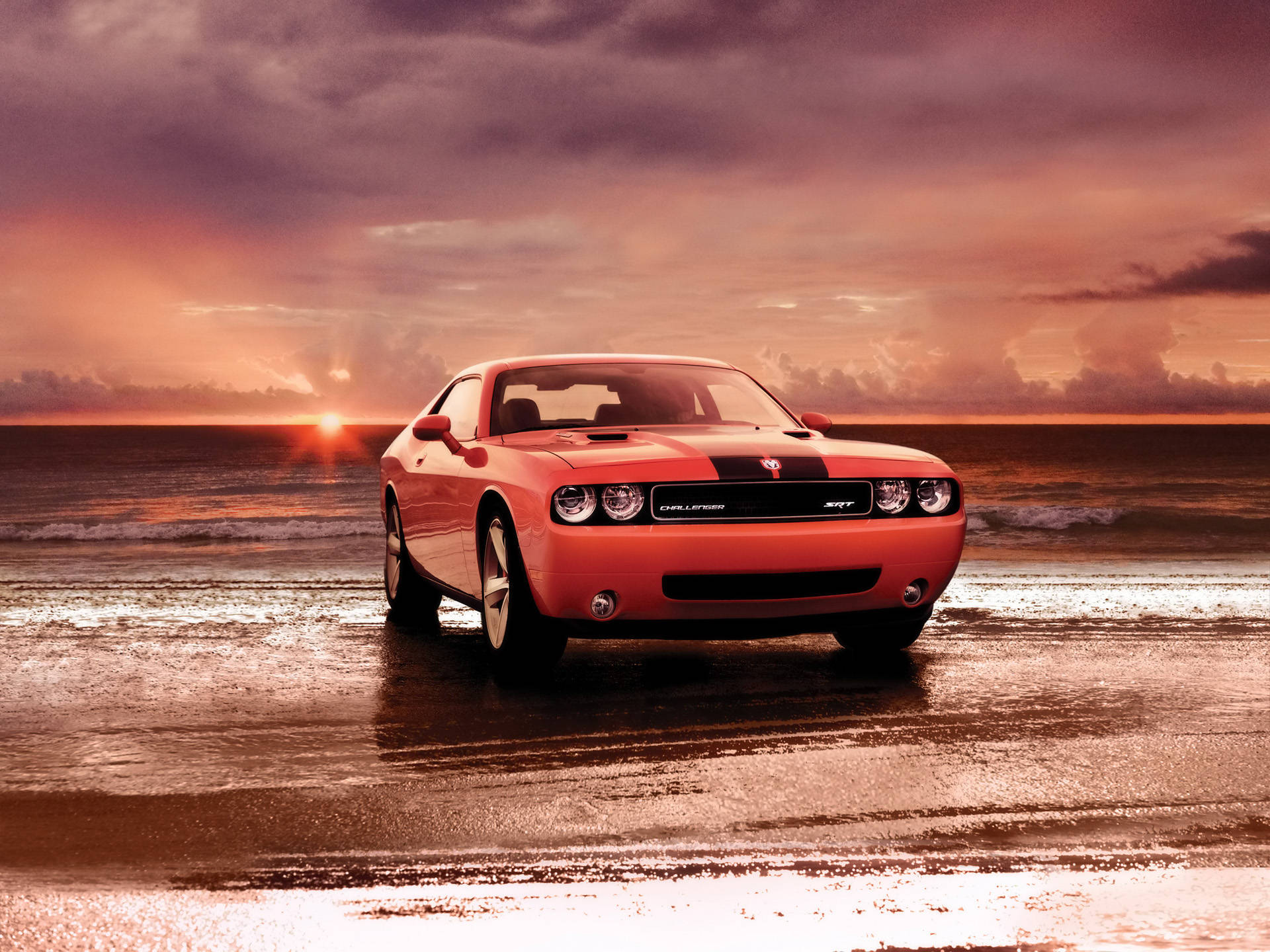 Challenger 桌布 壁紙 — 一輛鮮豔的橙色 Dodge Challenger SRT 停在日落時分的濕沙灘上，天空呈現戲劇性的紫色和橙色。