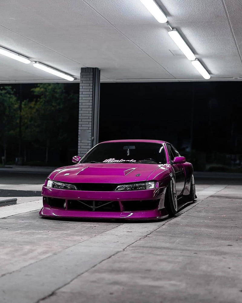 Nissan Silvia S14 桌布 壁紙 — 一輛鮮豔的洋紅色改裝跑車在夜間停放在光線昏暗的車庫中，置於螢光燈下。