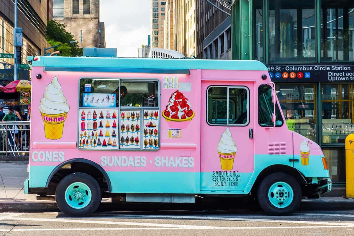 Ice Cream Truck 桌布 壁紙 — 一輛鮮豔的粉紅色和藍綠色冰淇淋車停在城市街道上，櫥窗裡展示著色彩繽紛的甜點菜單。