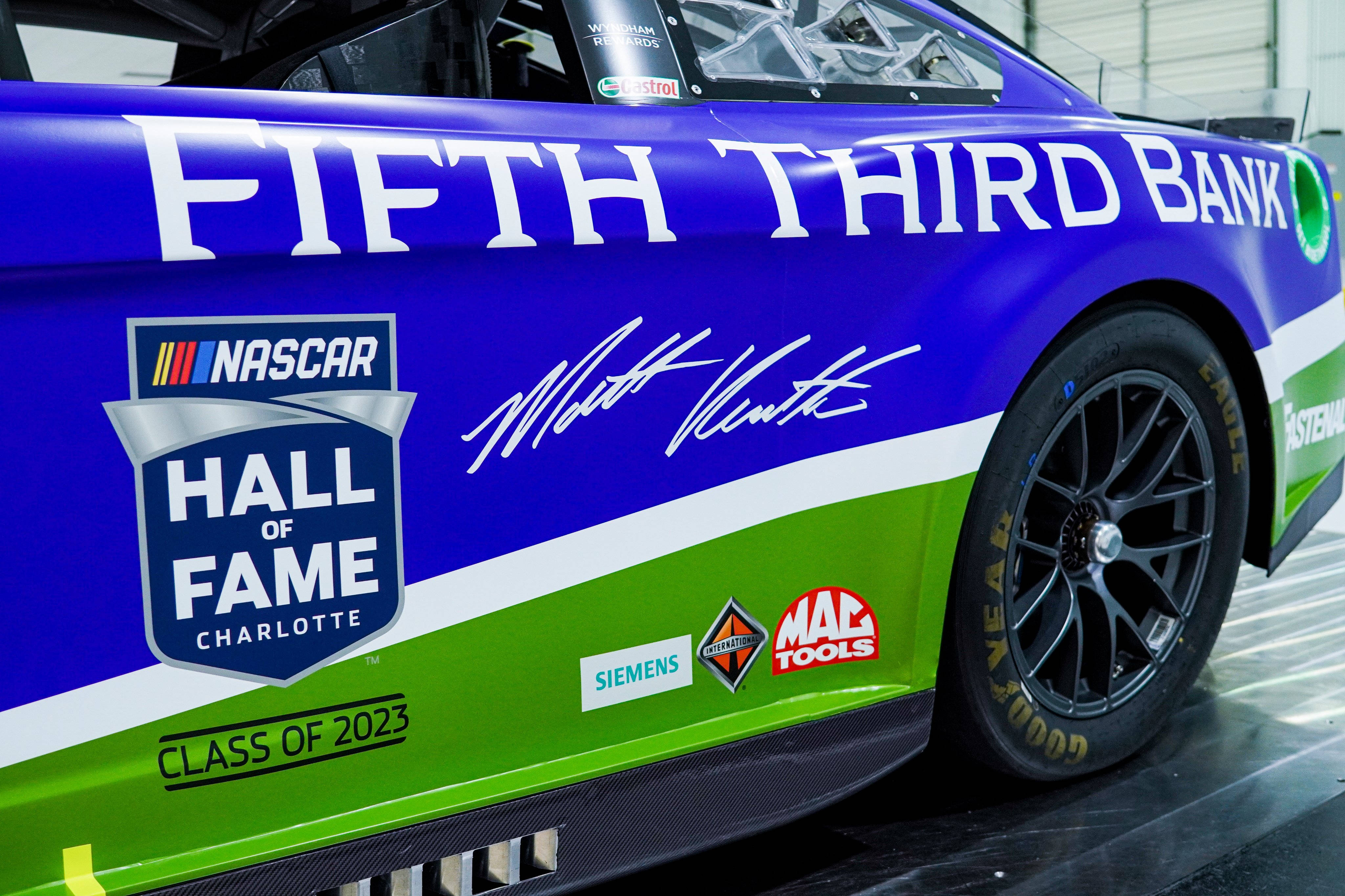 肌肉車 桌布 壁紙 — 一輛鮮豔的藍綠色NASCAR賽車，帶有Fifth Third Bank贊助和Hall of Fame Charlotte 2023貼紙，停在車庫中。