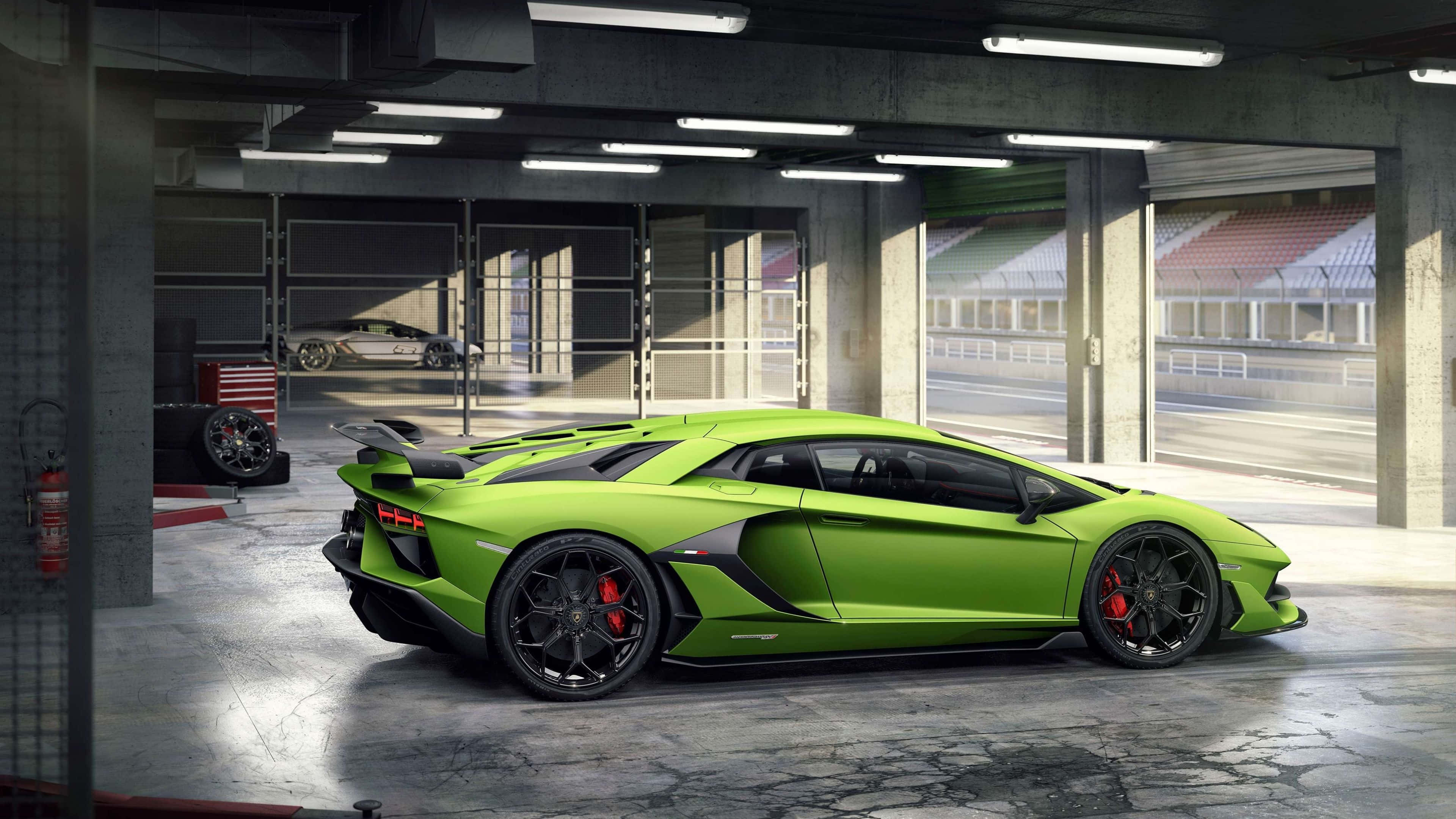 4K 藍寶堅尼 桌布 壁紙 — 一輛鮮豔的青檸綠色藍寶堅尼Aventador SVJ停放在混凝土車庫中，透過敞開的車庫門可以看到賽道。