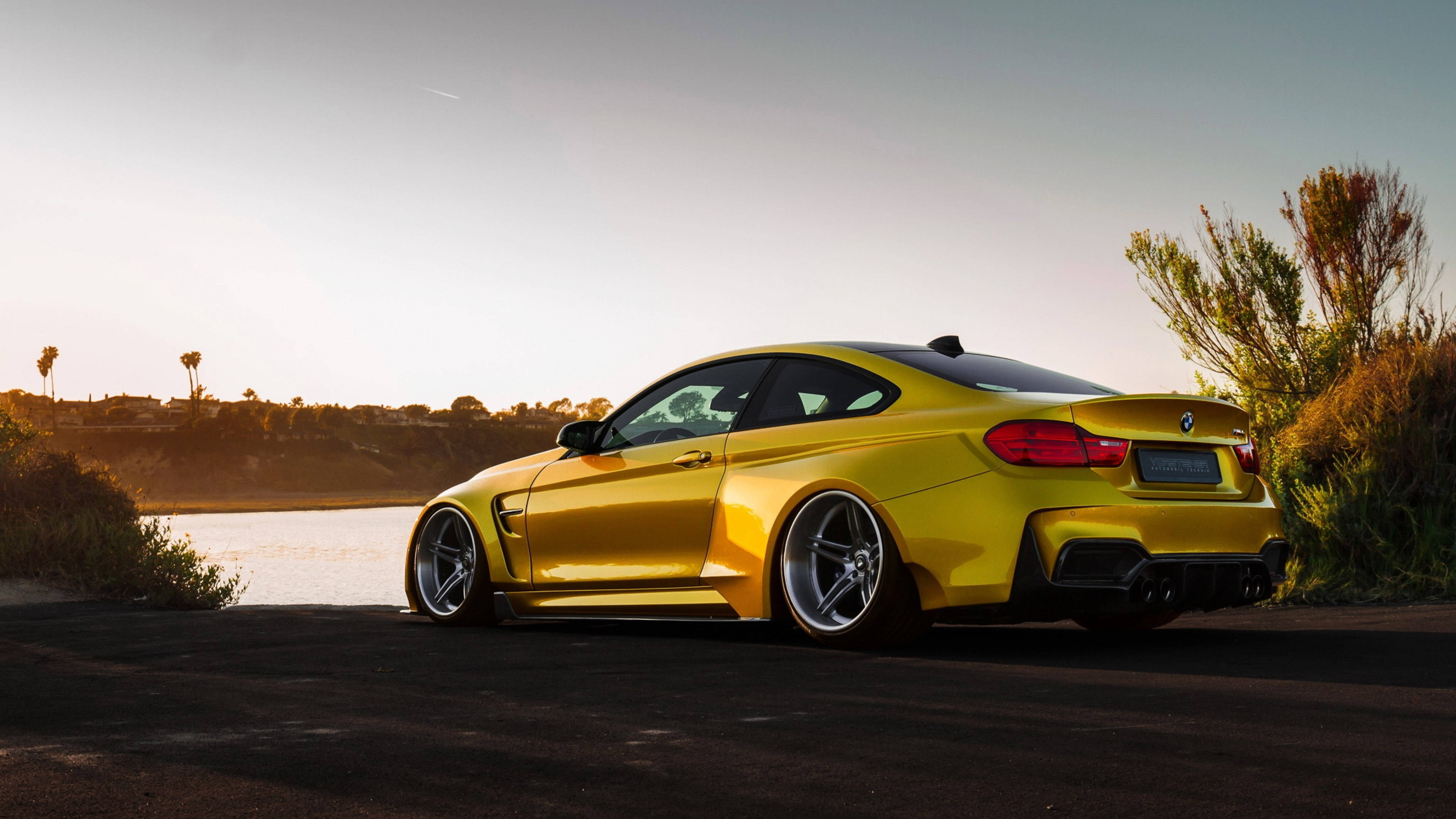 4K BMW 壁紙 桌布 壁紙 — 一輛鮮黃色BMW M4雙門跑車停泊在平靜的湖邊，正值黃金時刻，溫暖的光線投下長長的影子。