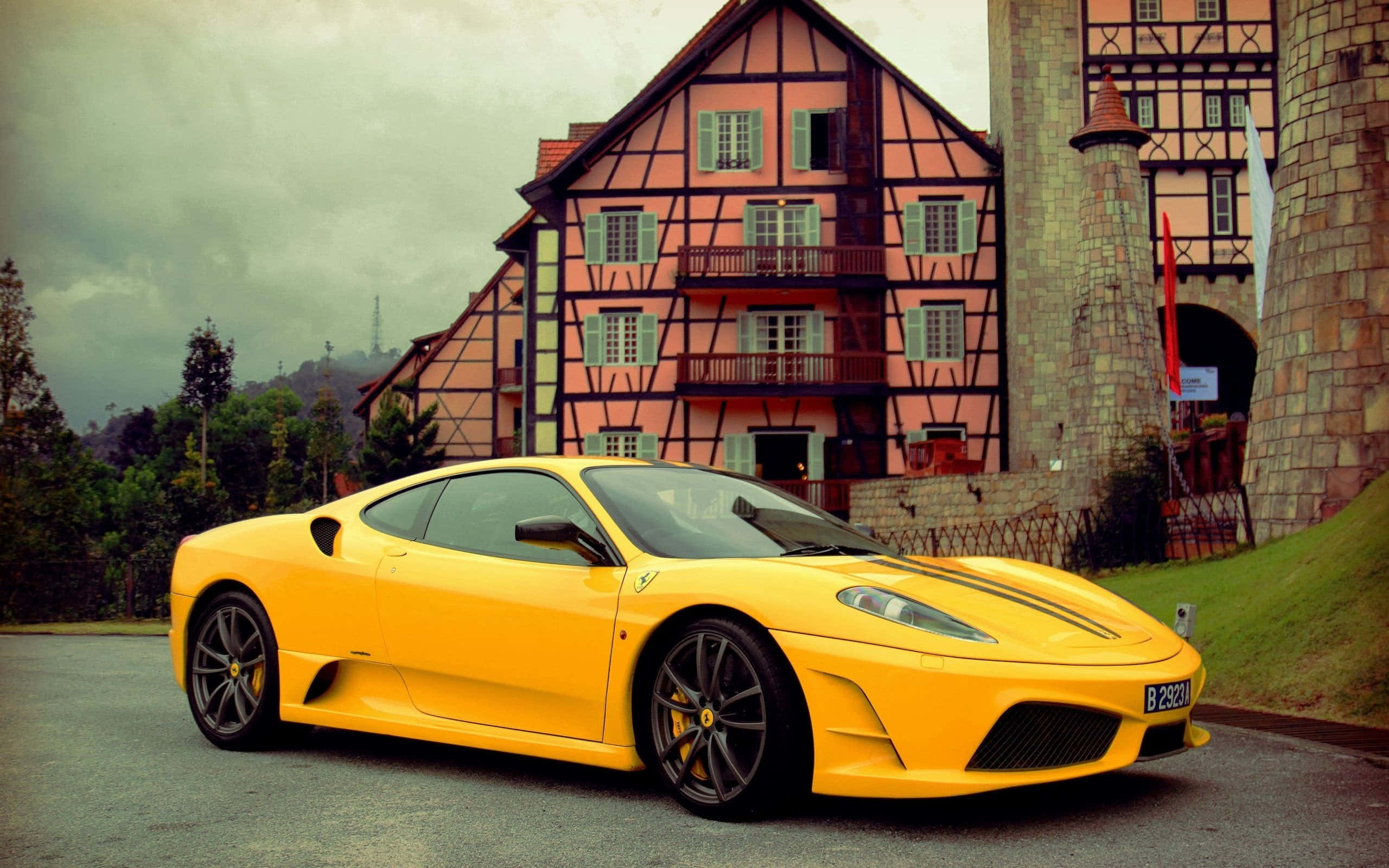 Ferrari F430 桌布 壁紙 — 一輛鮮黃色法拉利跑車停在一棟粉紅色半木造建築前，天空多雲。