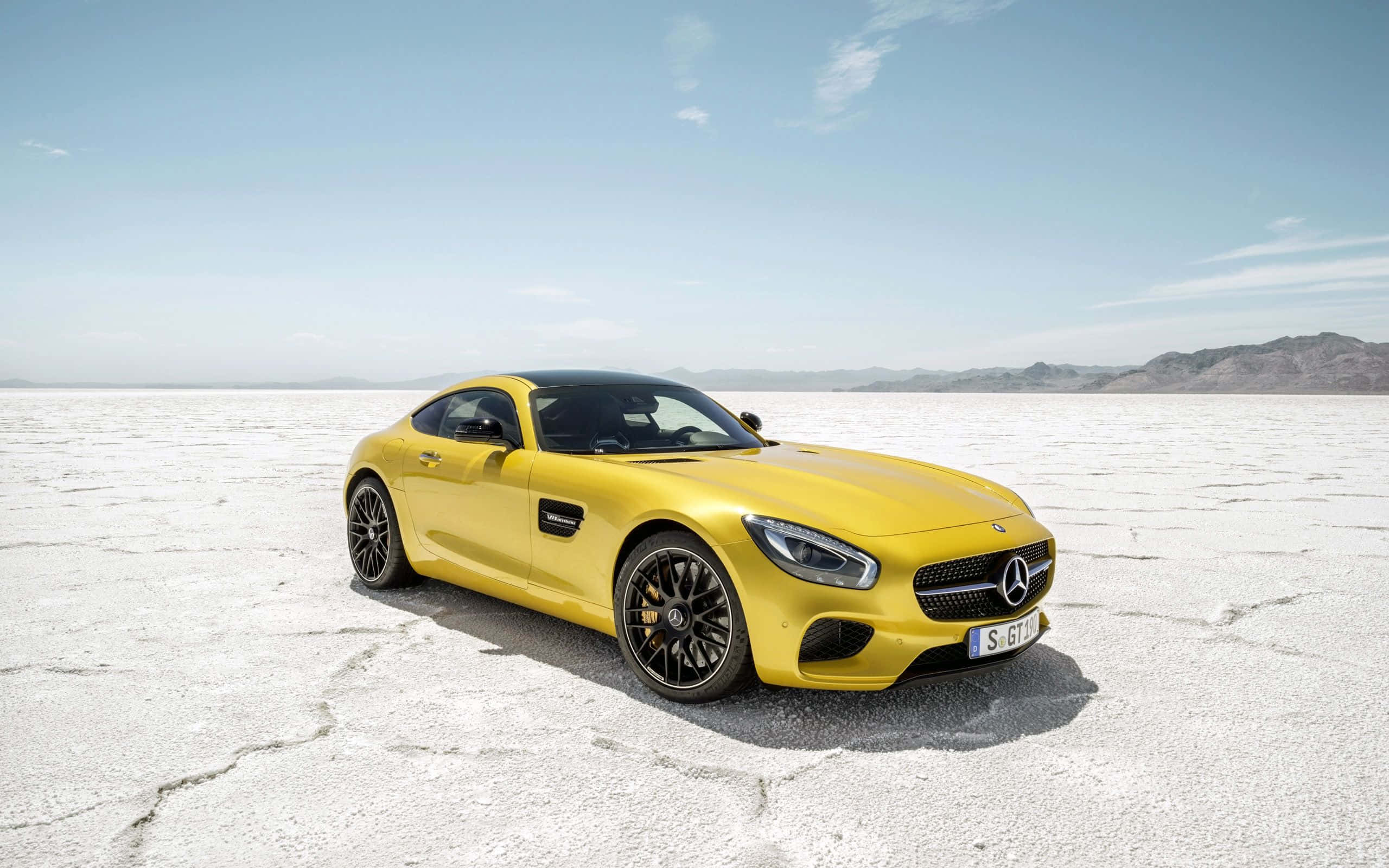 Mercedes 桌布 壁紙 — 一輛鮮黃色的 Mercedes-AMG GT S 跑車停放在龜裂的白色鹽灘上，天空清澈湛藍。