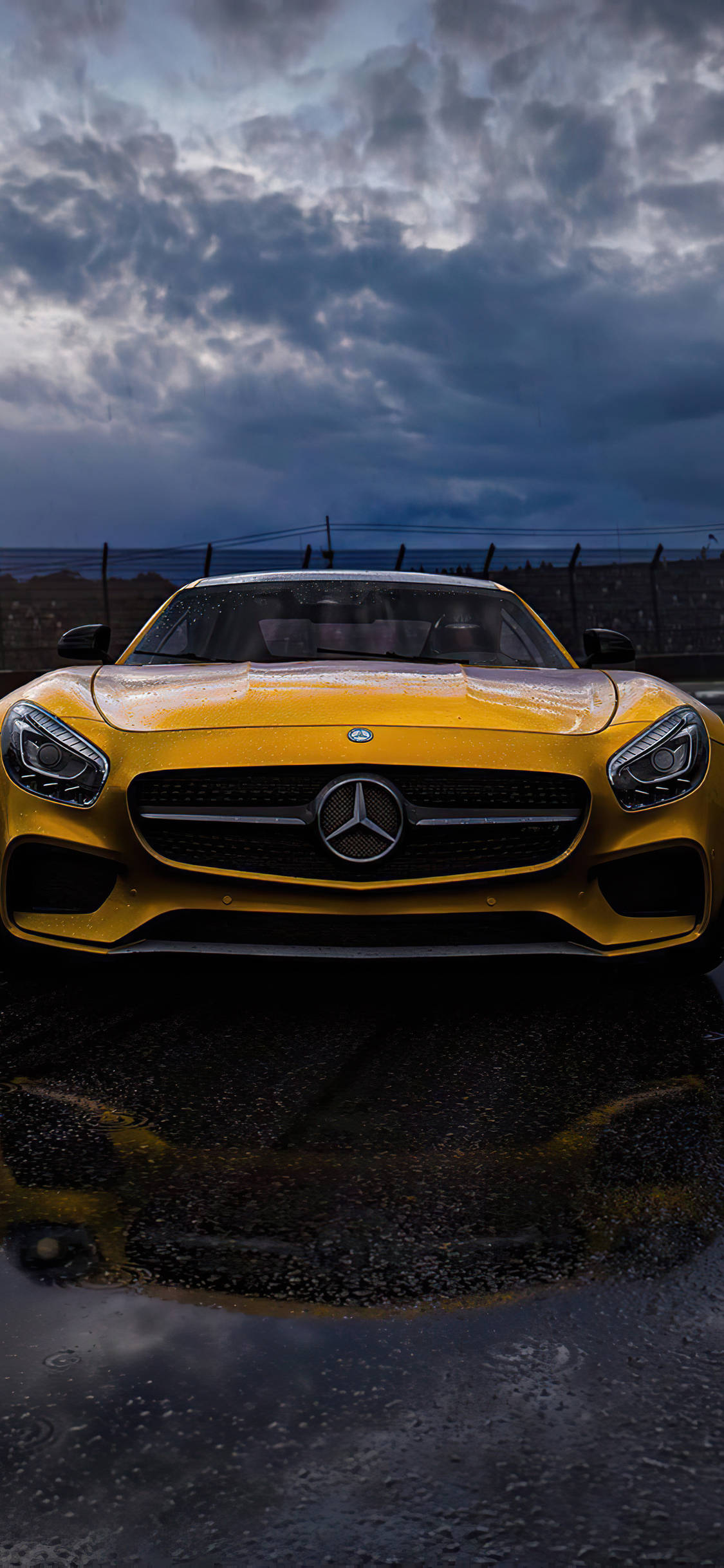 amg iPhone 桌布 壁紙 — 一輛鮮黃色的 Mercedes-AMG GT 跑車在戲劇性的暴風雨天空下閃閃發光，倒映在濕漉漉的瀝青路面上。