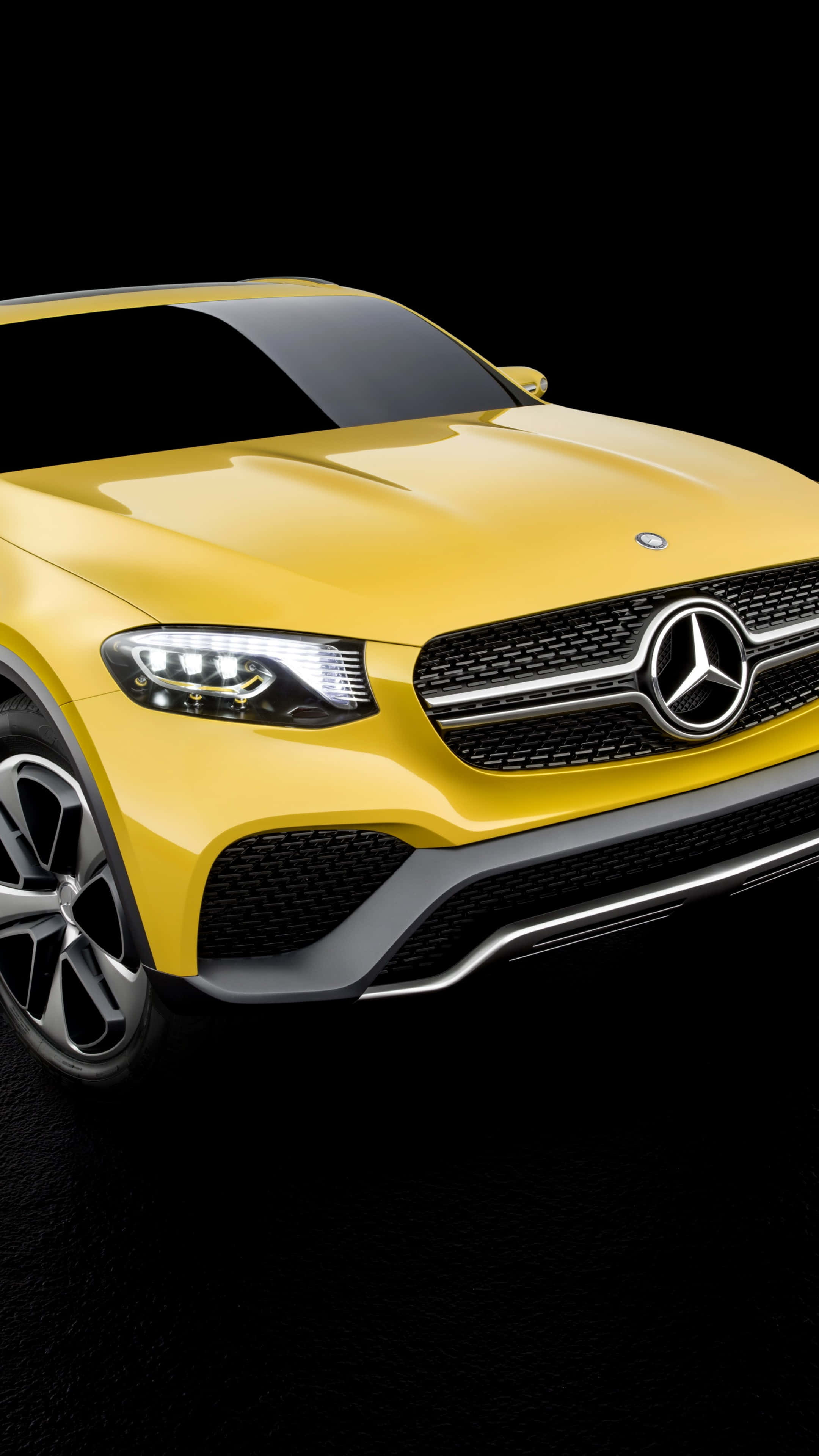 iPhone X Mercedes 桌布 壁紙 — 一輛鮮黃色的 Mercedes-Benz SUV 在攝影棚燈光下，於純黑背景上閃閃發光。