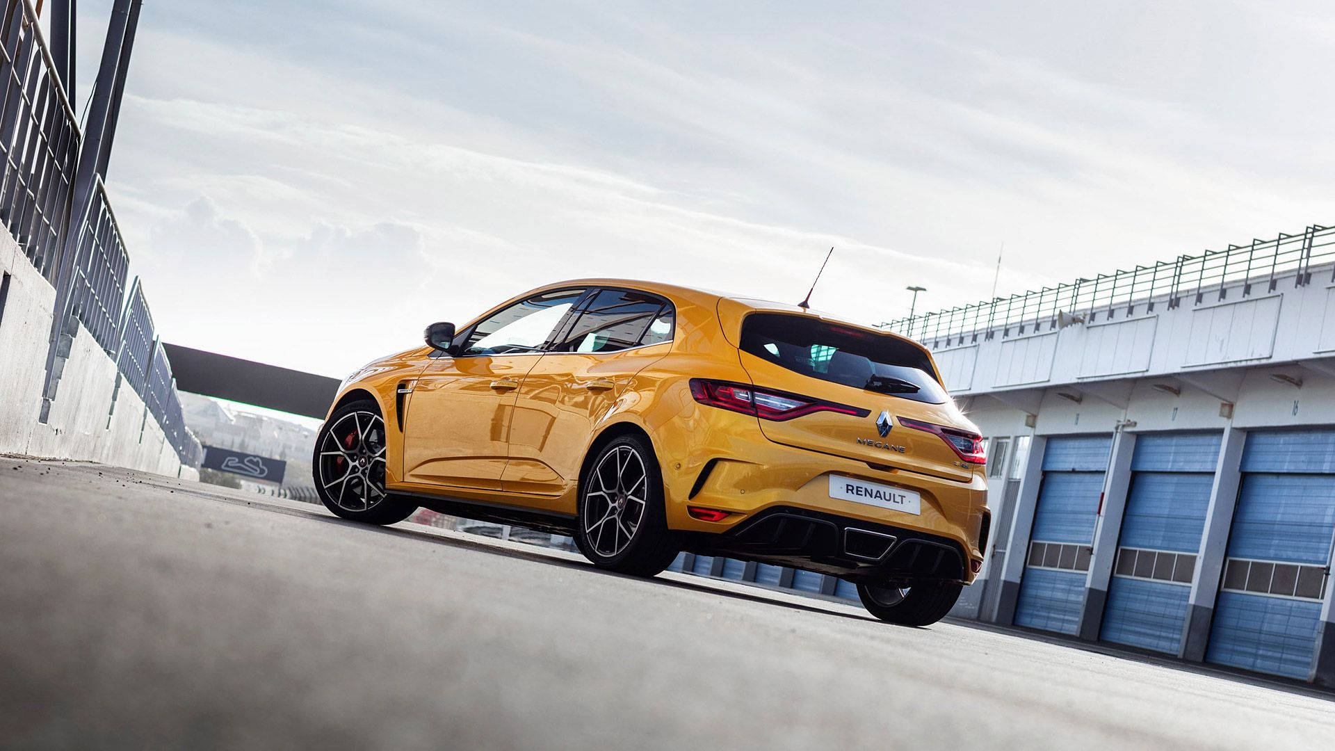 Renault 桌布 壁紙 — 一輛鮮黃色的Renaultsport R.S. 01跑車停放在混凝土賽道上，旁邊是藍色車門的現代車庫。