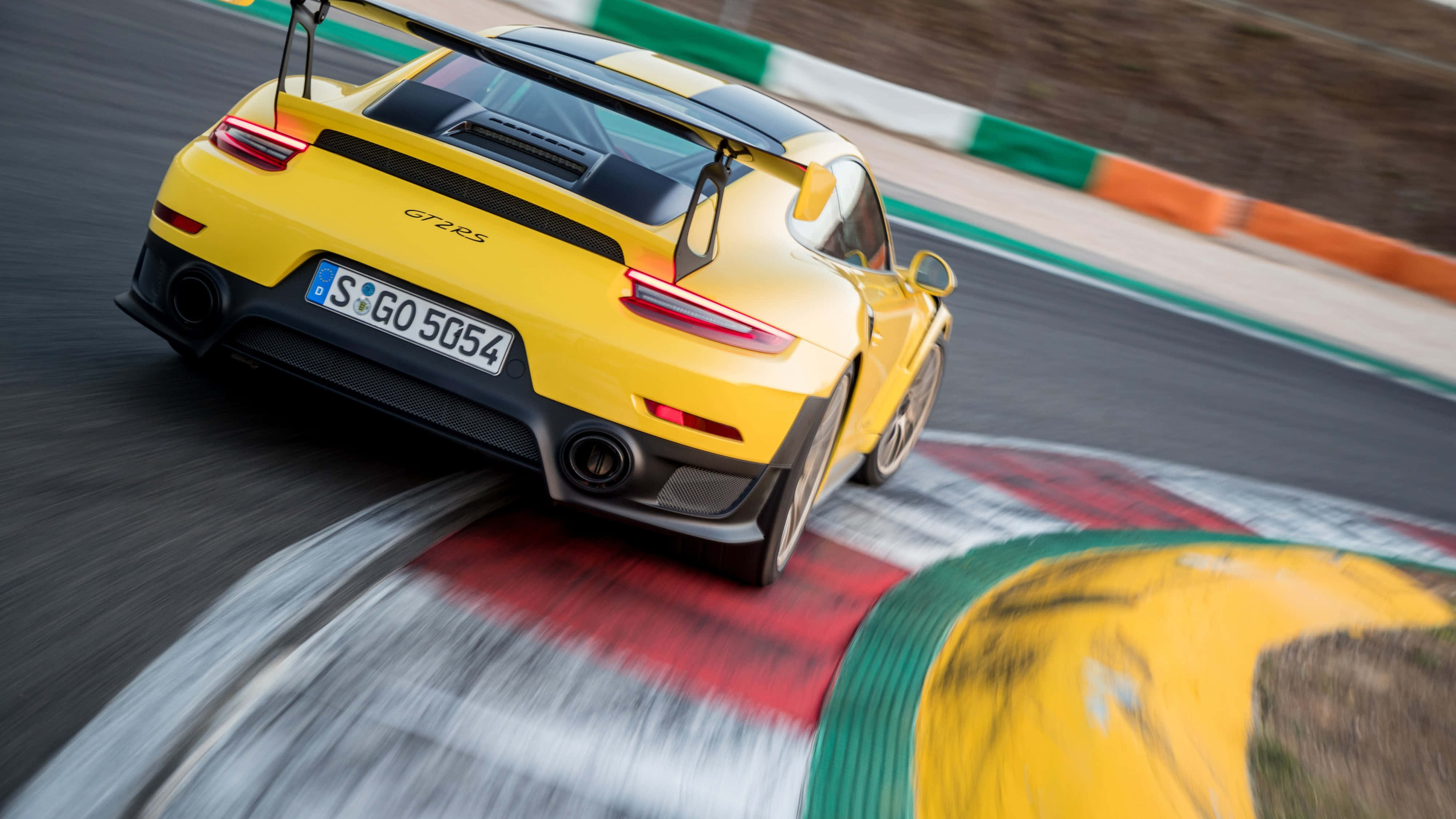 桌布 壁紙 — 一輛鮮黃色的保時捷911 GT2 RS在賽道彎位疾馳，動態模糊效果強調速度感。