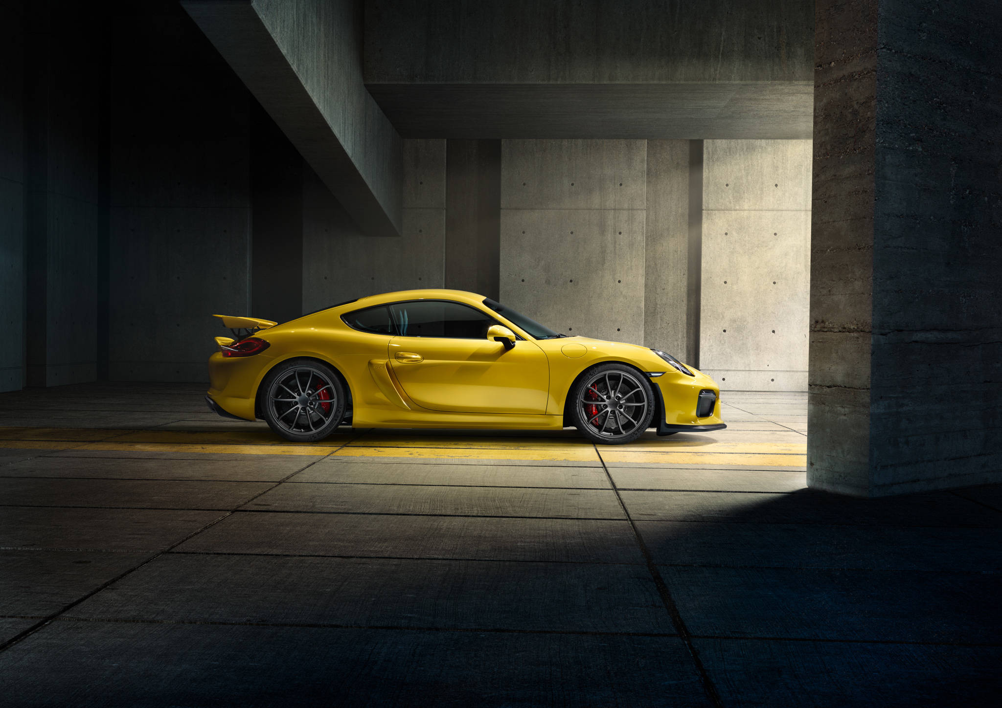 保時捷 桌布 壁紙 — 一輛鮮黃色的保時捷Cayman GT4停在混凝土車庫中，戲劇性的燈光投下長長的陰影。