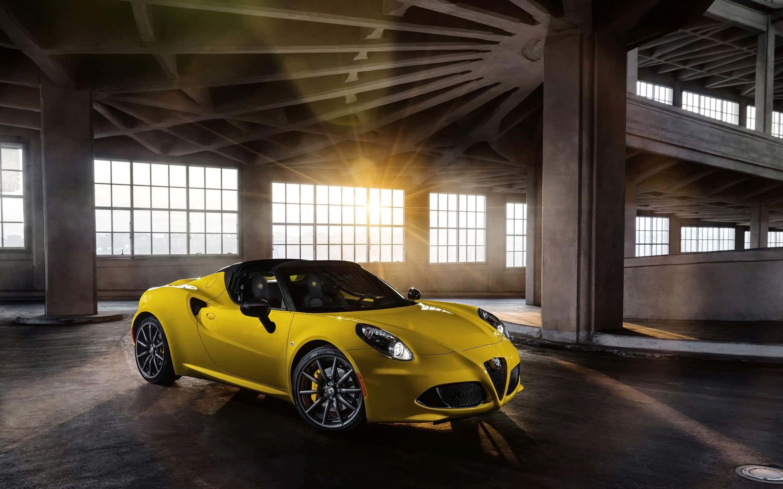 Alfa Romeo 4c 桌布 壁紙 — 一輛鮮黃色的愛快羅密歐Spider敞篷車在金色夕陽下閃耀，陽光穿過破舊工業倉庫的大窗戶灑落。