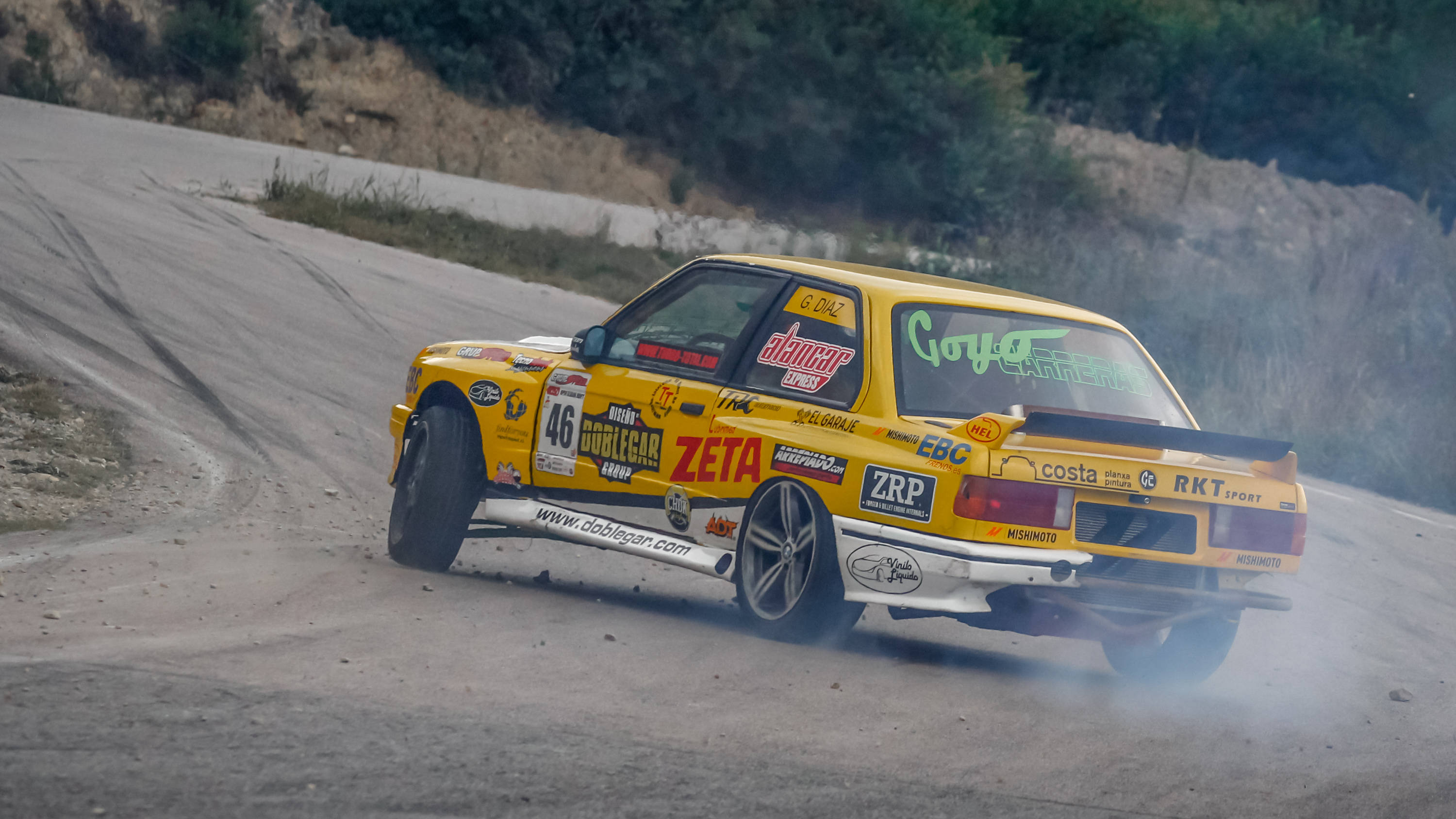 rally 桌布 壁紙 — 一輛鮮黃色的拉力賽車在塵土飛揚的山路上急劇飄移，揚起煙霧和碎石。