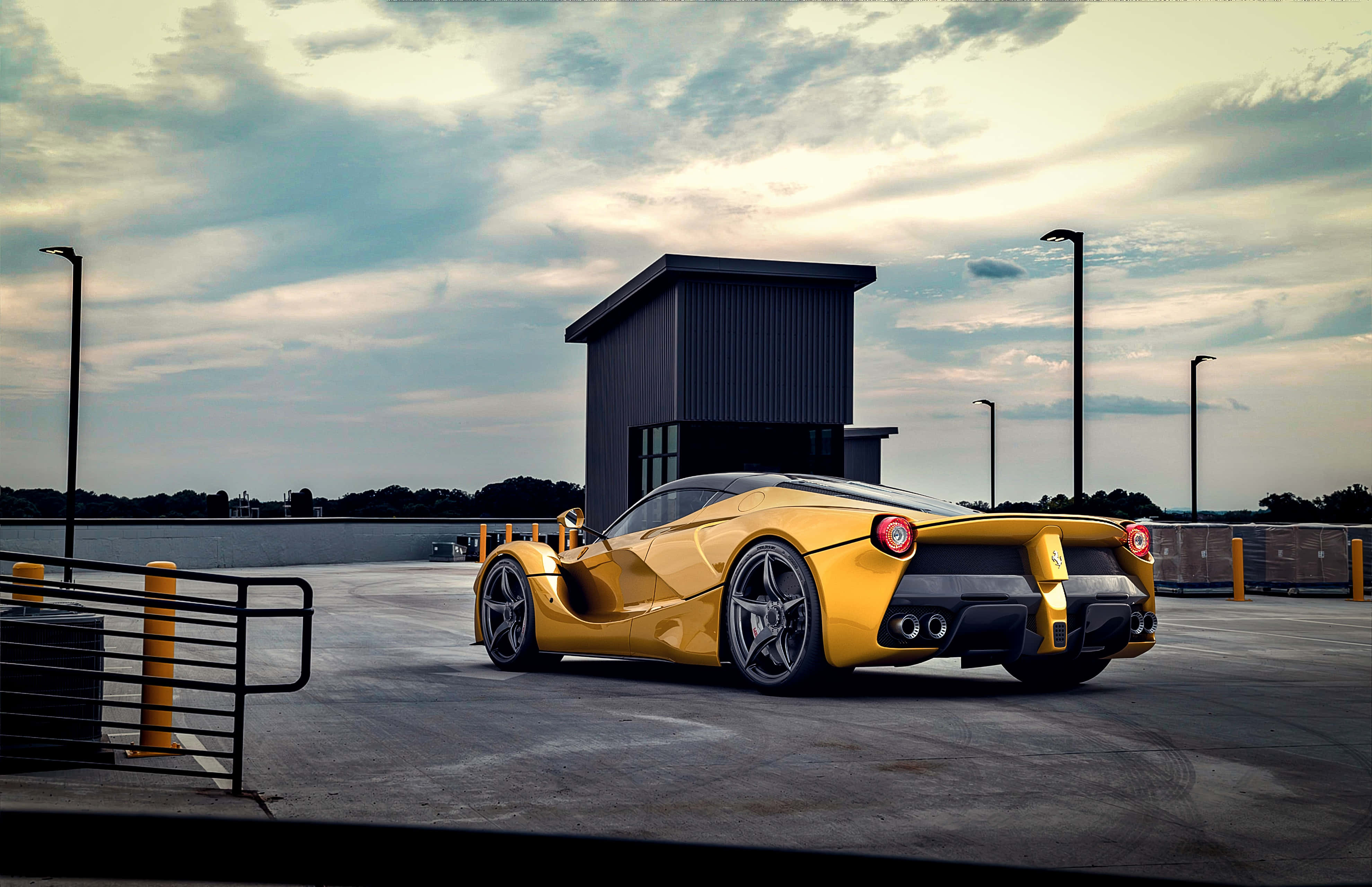 桌布 壁紙 — 一輛鮮黃色的法拉利 LaFerrari 停在混凝土場地上，天空多雲，黃昏時分，附近有工業建築。