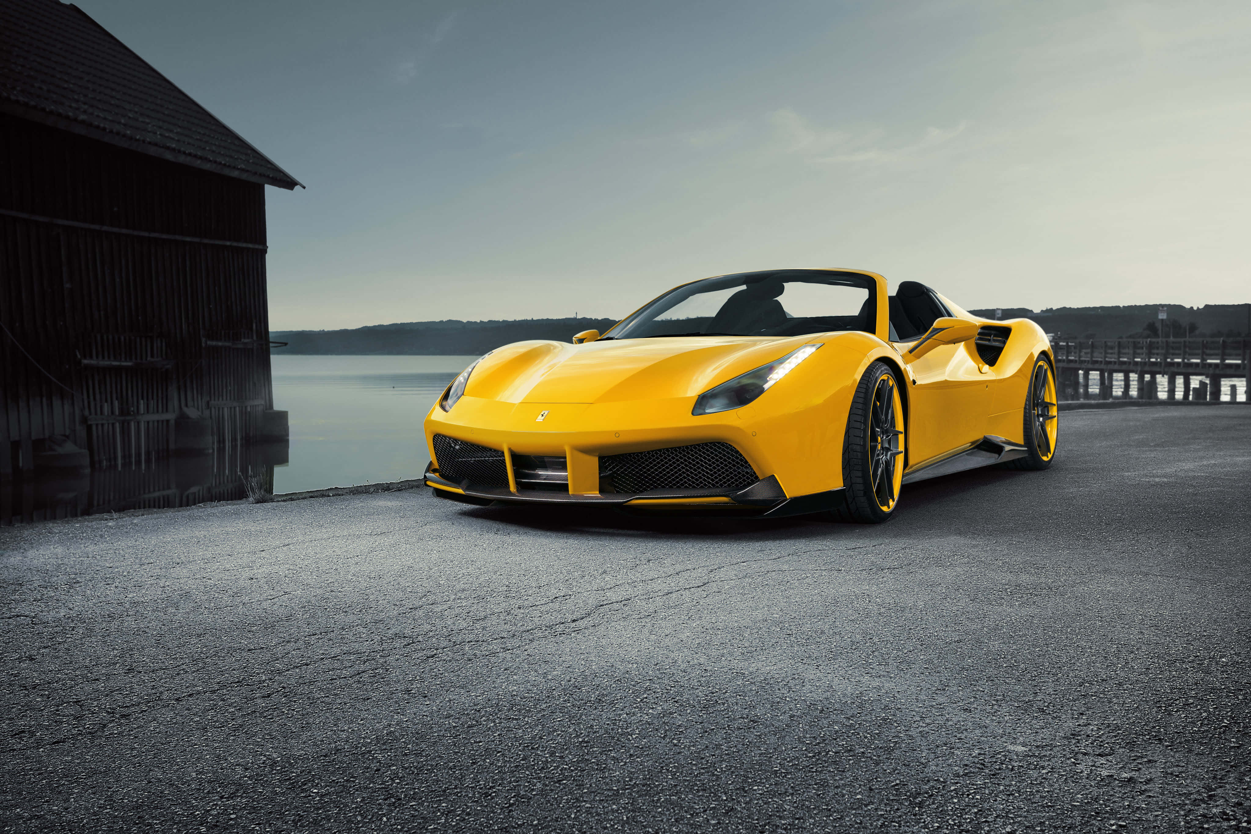 Ferrari 488 Spider 桌布 壁紙 — 一輛鮮黃色的法拉利跑車停在寧靜湖泊旁的瀝青路上，背景有一座木製穀倉。