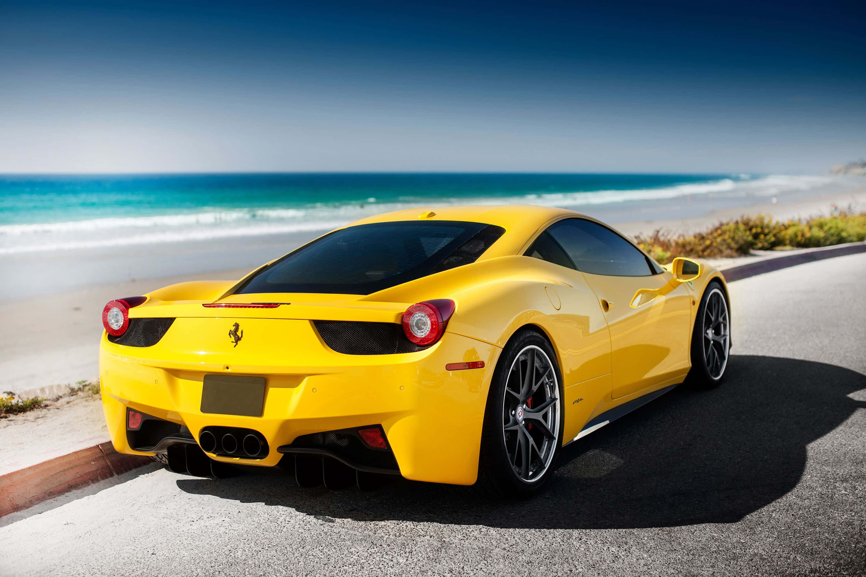 Yellow Car 桌布 壁紙 — 一輛鮮黃色的法拉利跑車停泊在海岸公路上，背後有藍綠色的海浪拍打。