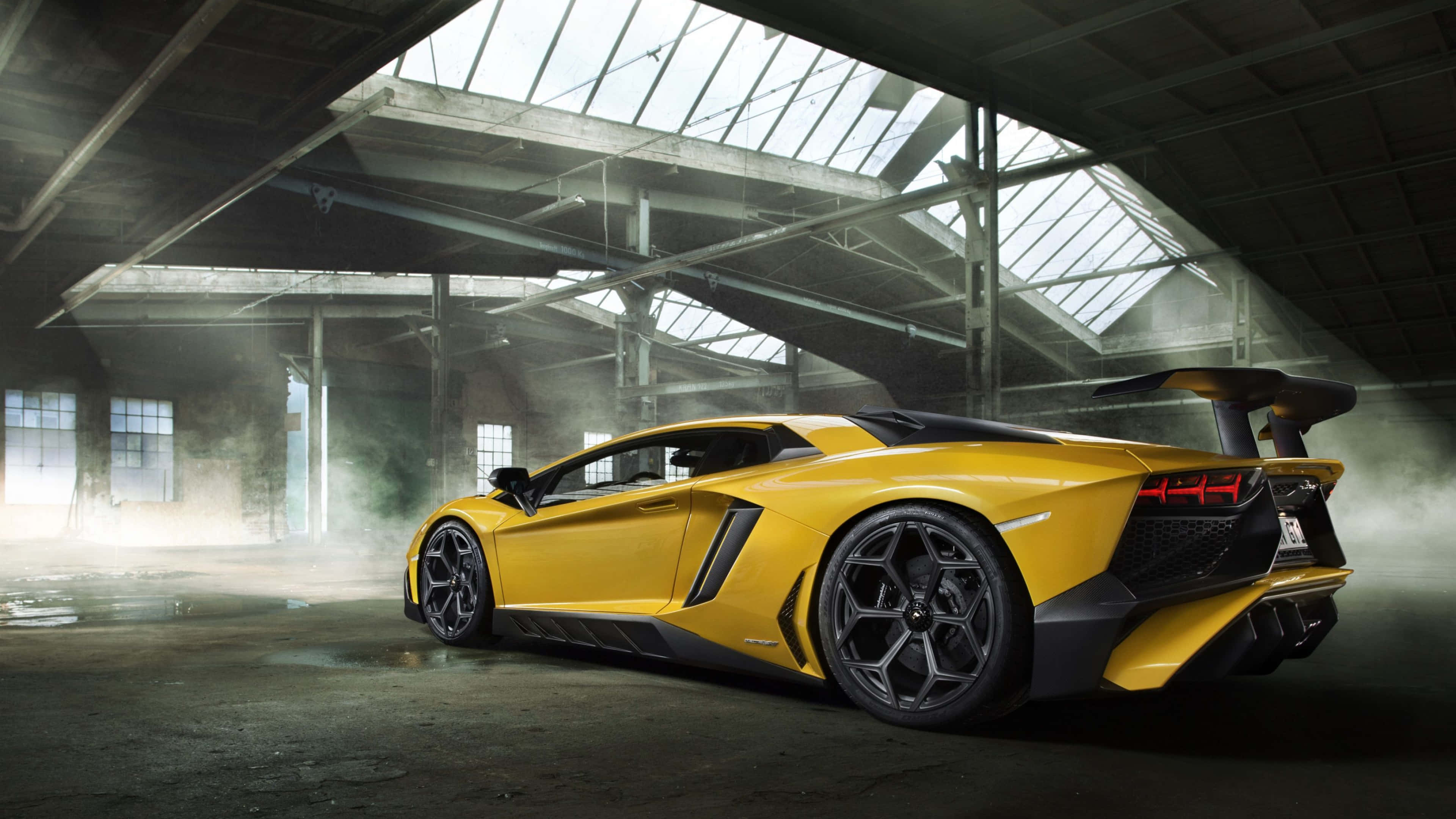 桌布 壁紙 — 一輛鮮黃色的藍寶堅尼 Aventador SVJ 在灰塵滿佈的廢棄倉庫中，於工業天窗下閃閃發光。
