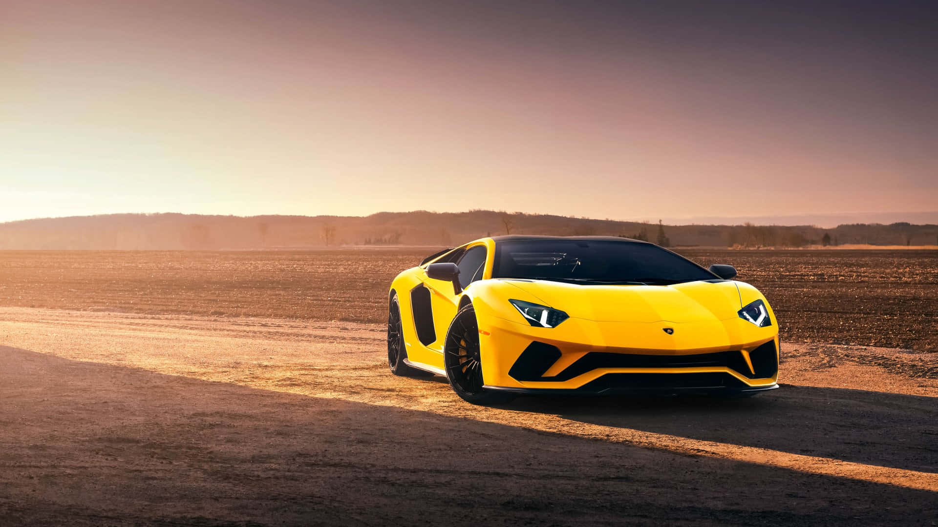 蘭博基尼 桌布 壁紙 — 一輛鮮黃色的藍寶堅尼 Aventador 在日落時分停泊在塵土飛揚的道路上，溫暖的金色陽光投下長長的影子。