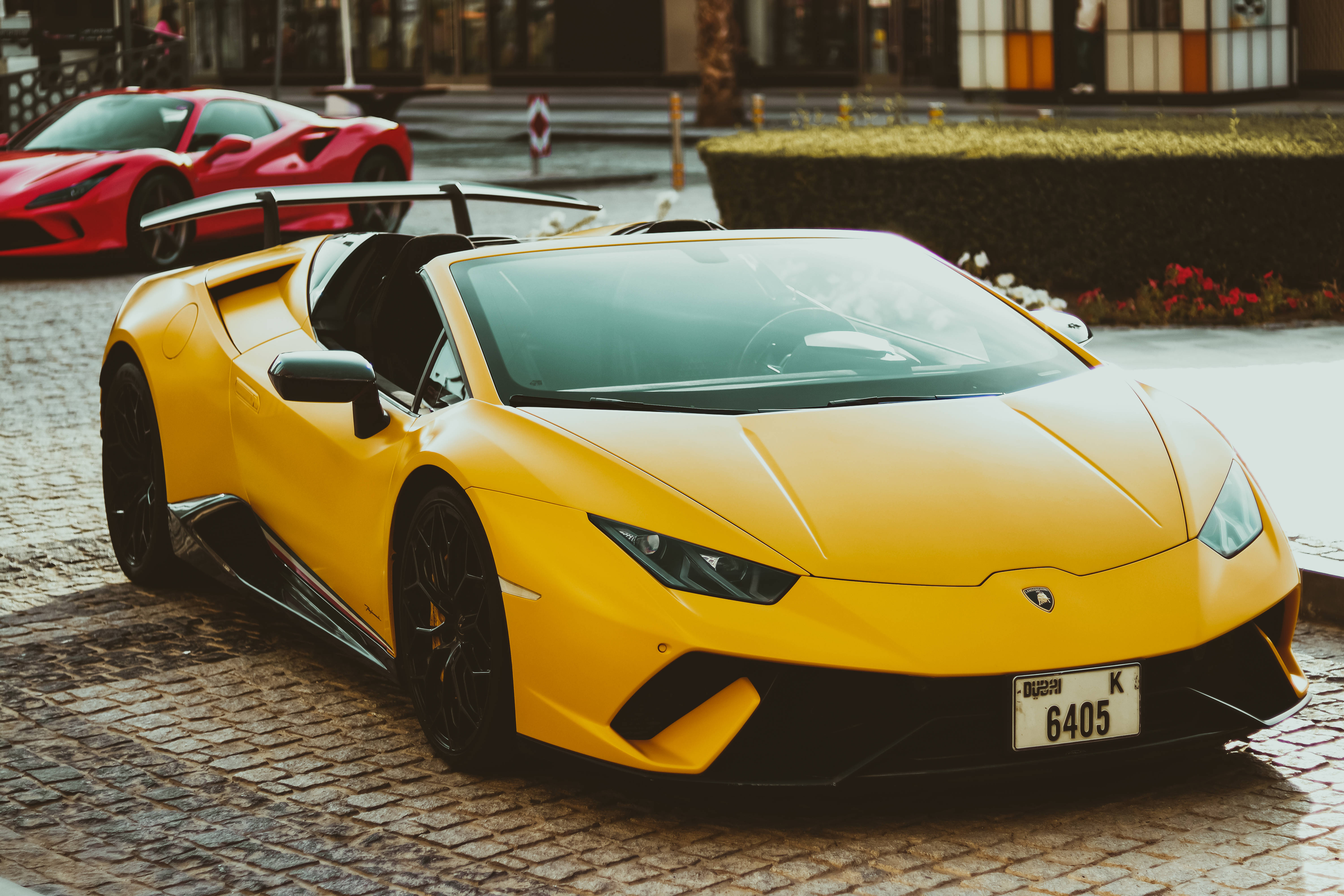 4K Lamborghini 桌布 壁紙 — 一輛鮮黃色的藍寶堅尼 Huracán Spyder 停放在濕漉漉的鵝卵石街道上，背景有一輛紅色法拉利。