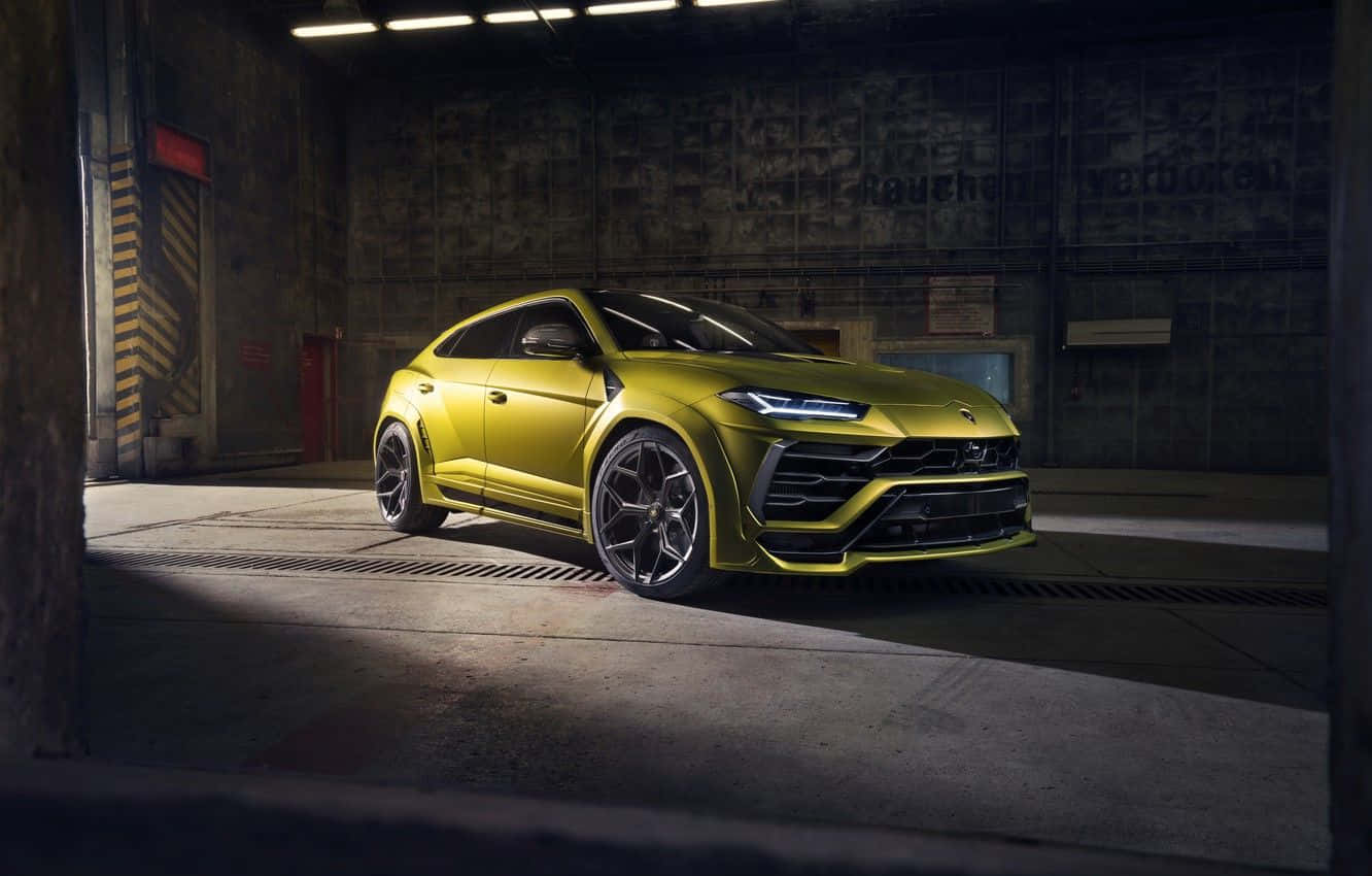 Lamborghini Urus 桌布 壁紙 — 一輛鮮黃色的藍寶堅尼 Urus SUV 在光線強烈的工業車庫內閃閃發光。