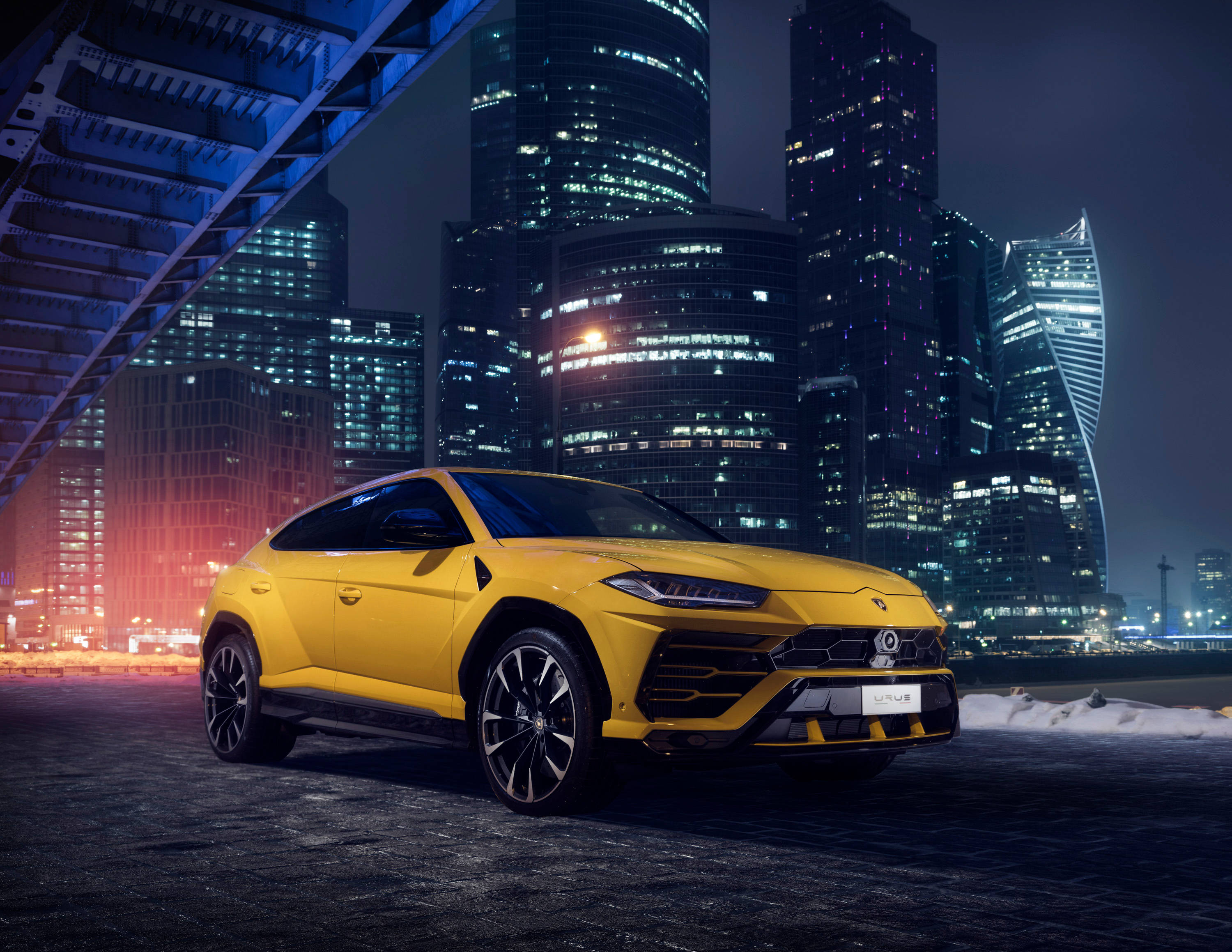 lambo 桌布 壁紙 — 一輛鮮黃色的藍寶堅尼 Urus SUV 在霓虹燈下閃耀，背景是雪夜的都市天際線。