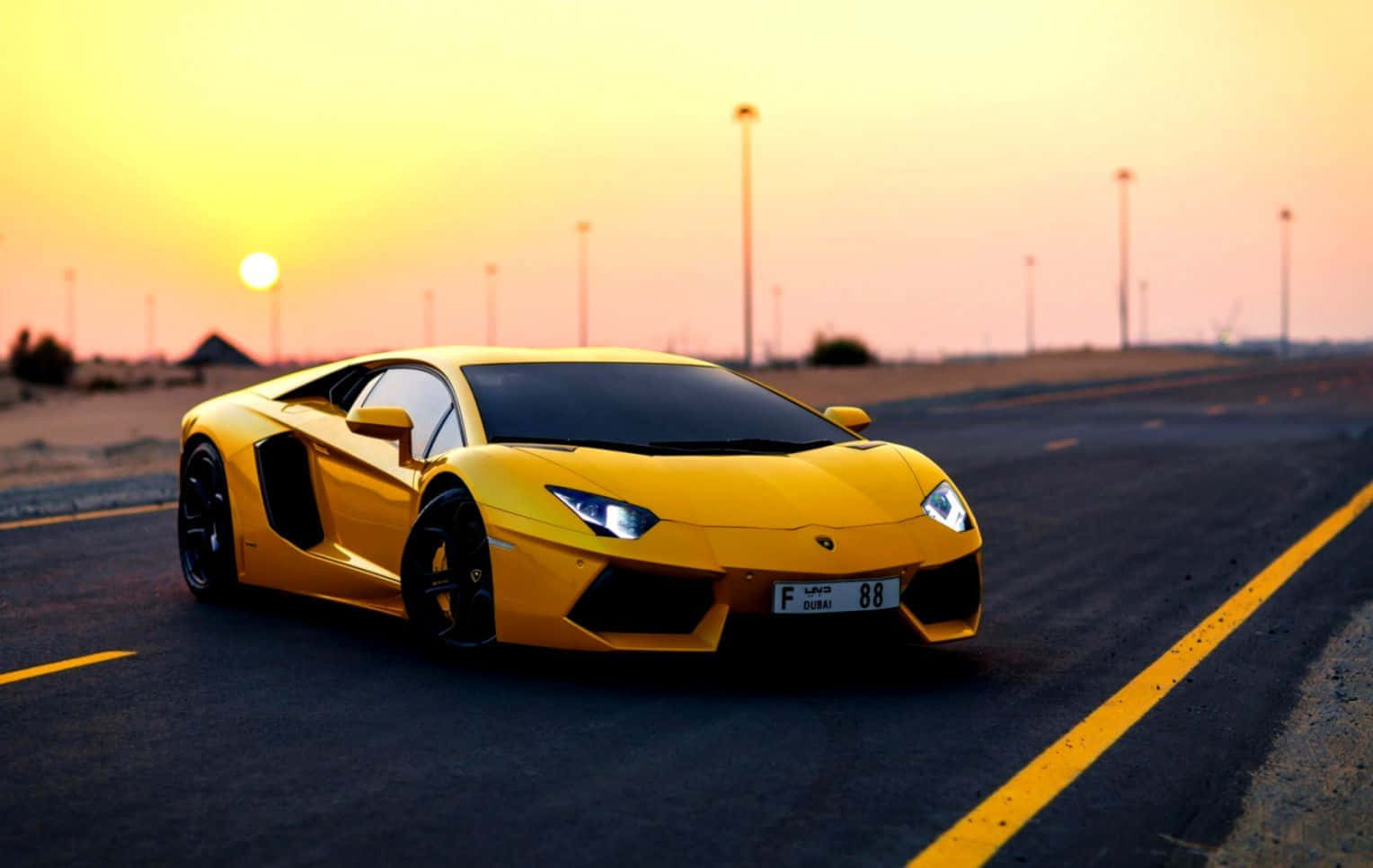 Yellow Car 桌布 壁紙 — 一輛鮮黃色的藍寶堅尼Aventador在日落時分沿沙漠高速公路飛馳，溫暖的金色光芒沐浴著整個場景。