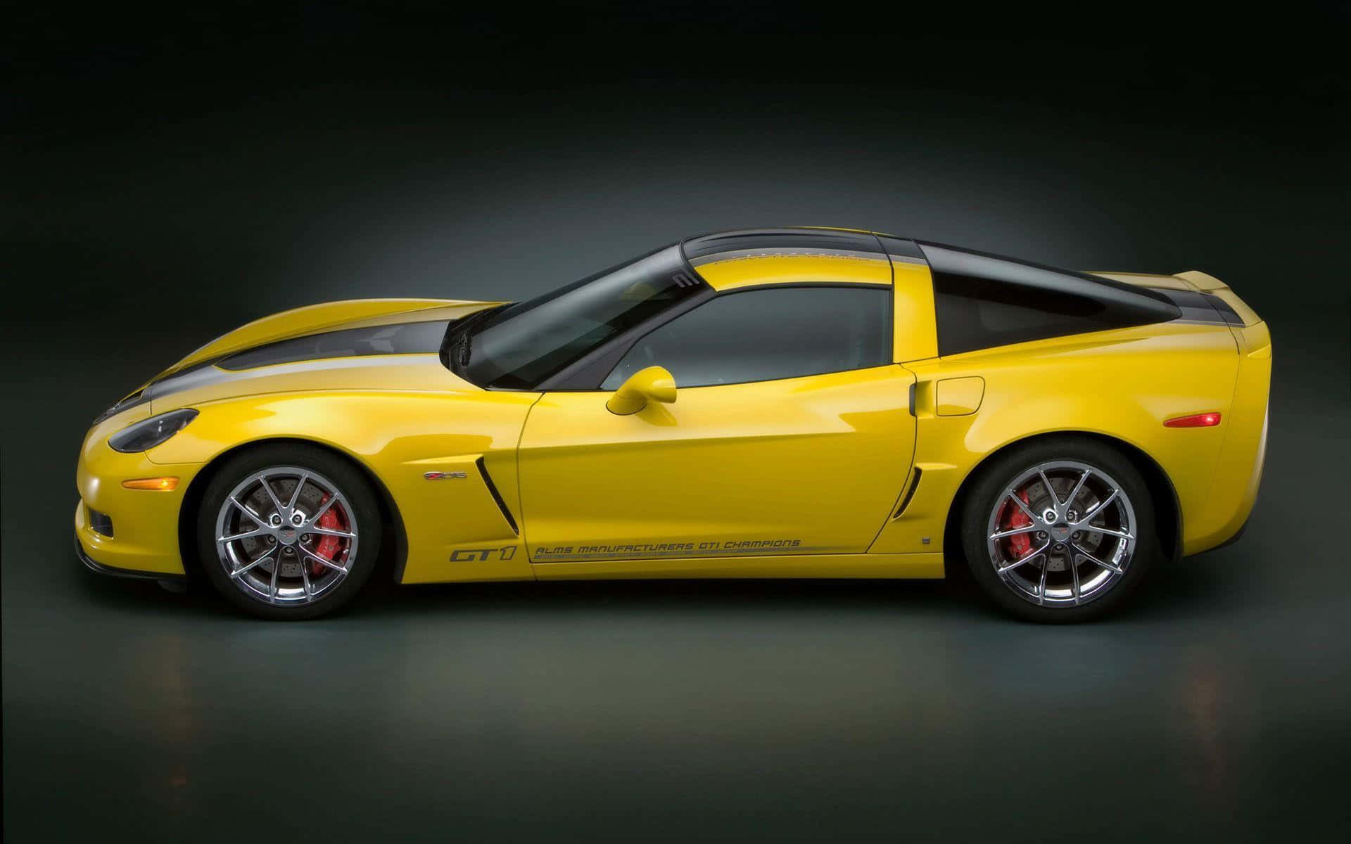 chevy 桌布 壁紙 — 一輛鮮黃色的雪佛蘭Corvette GT1跑車，帶有黑色賽車條紋和紅色制動卡鉗，在黑暗的攝影棚環境中展示。