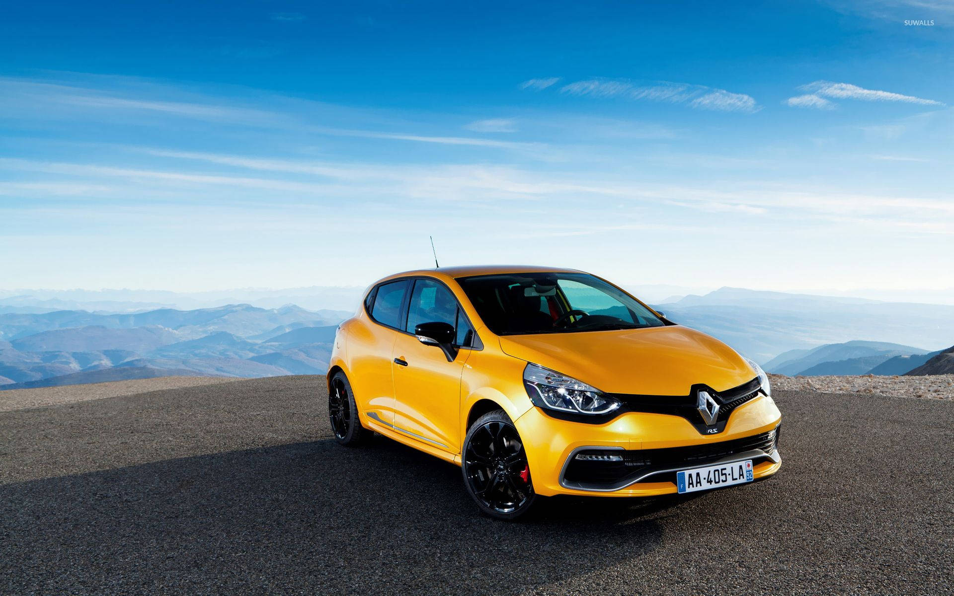 Renault 桌布 壁紙 — 一輛鮮黃色的雷諾Clio RS停在山頂觀景點，背景是層疊的藍色山脈和晴朗的天空。