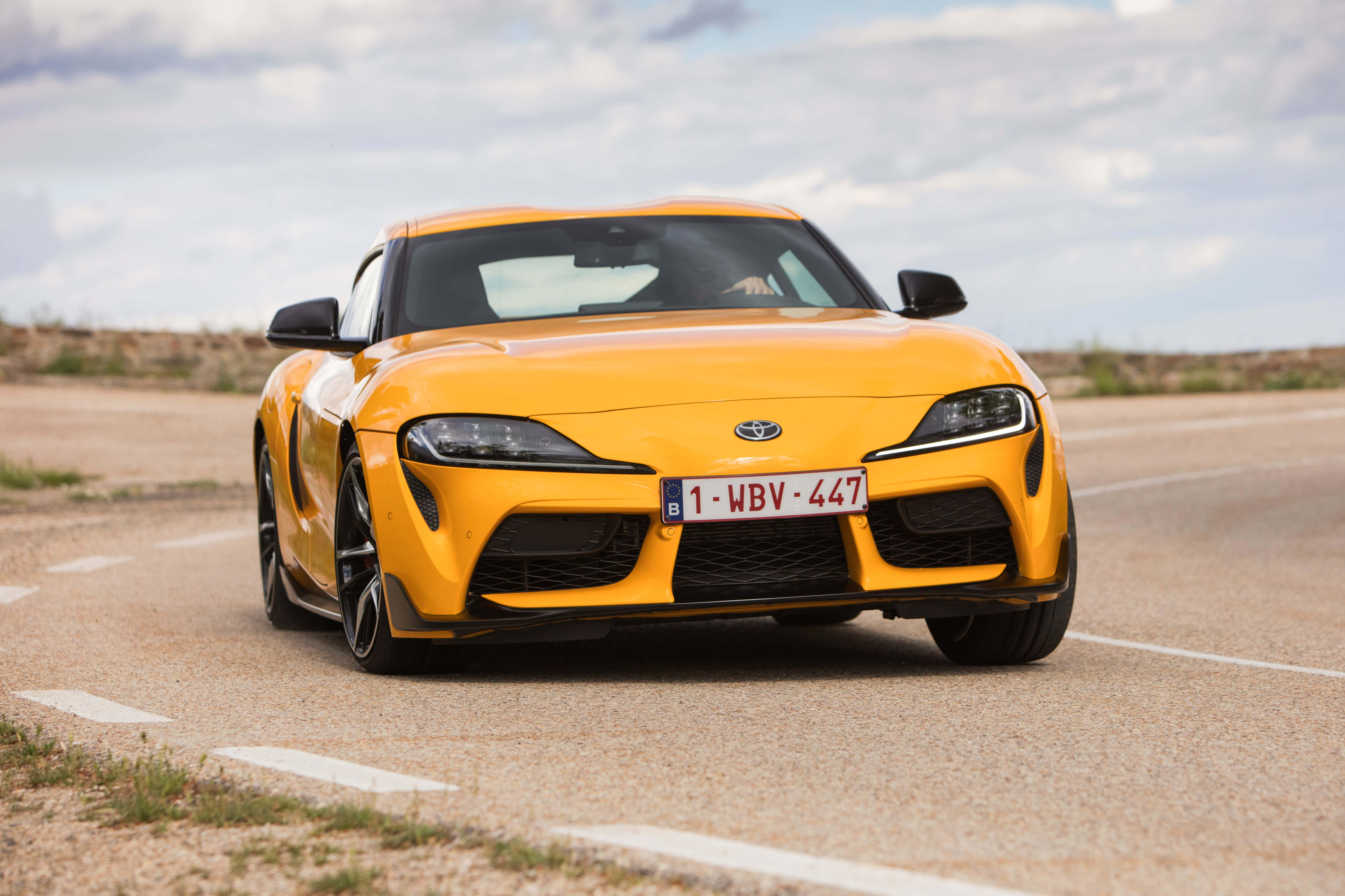 Supra 桌布 壁紙 — 一輛鮮黃色豐田Supra跑車停在沙漠公路上，天空多雲。