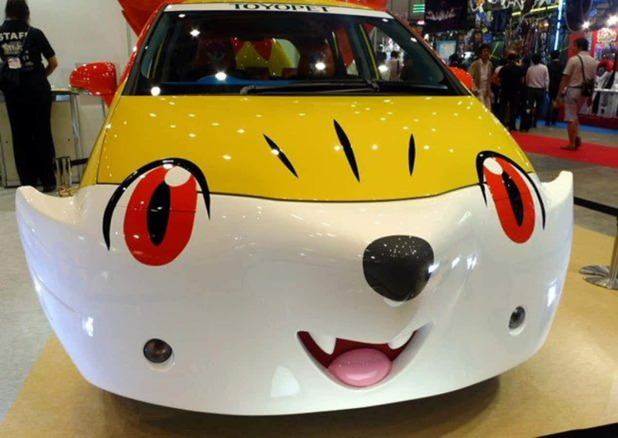 搞笑 桌布 壁紙 — 一輛黃白相間、造型像卡通貓的汽車，有紅色眼睛、粉紅色舌頭和黑色鬍鬚，在車展上展出。