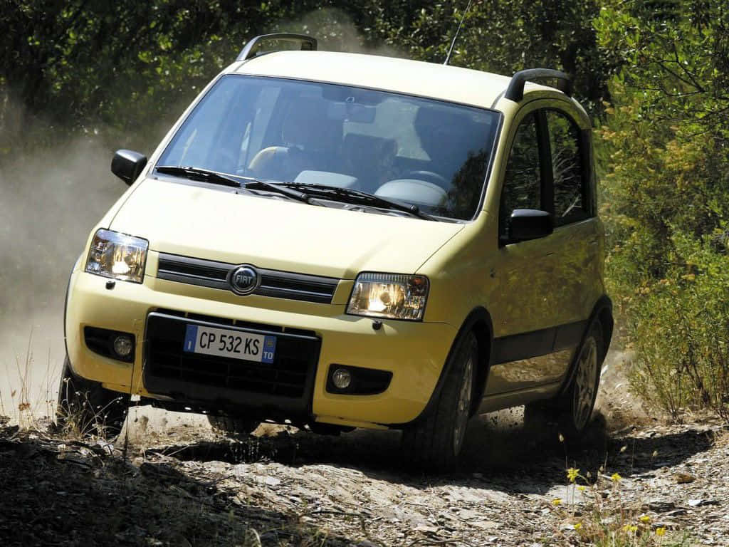 Fiat Panda 桌布 壁紙 — 一輛黃色Fiat Panda在陽光明媚下駛過塵土飛揚的森林小徑，揚起泥土和碎石。