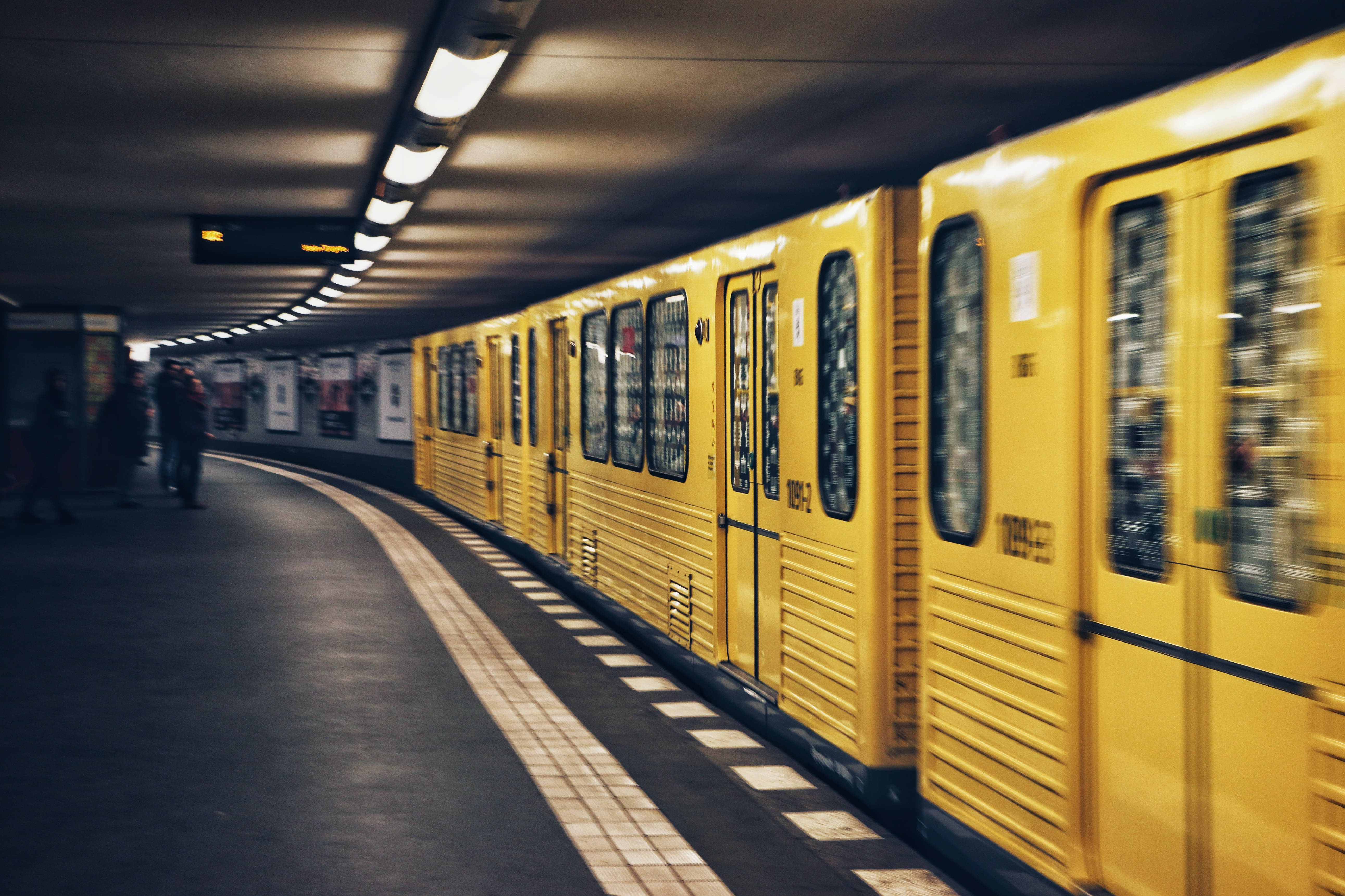 the yellow 桌布 壁紙 — 一輛黃色地鐵列車在燈光昏暗的月台上掠過，背景有乘客在等候。
