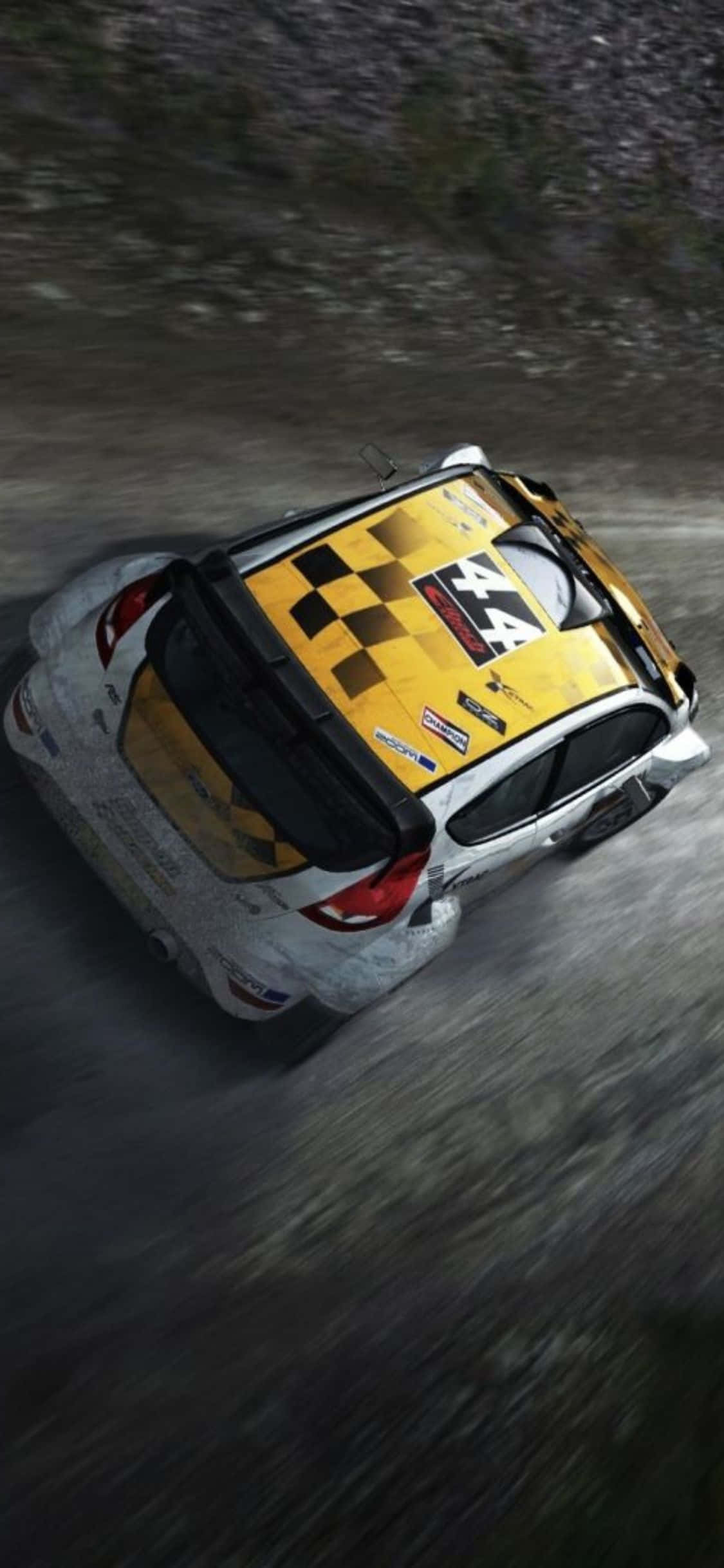 iPhone Xs Dirt Rally 桌布 壁紙 — 一輛黃黑相間的拉力賽車從俯視角度在泥濘的林間小徑上飛馳。