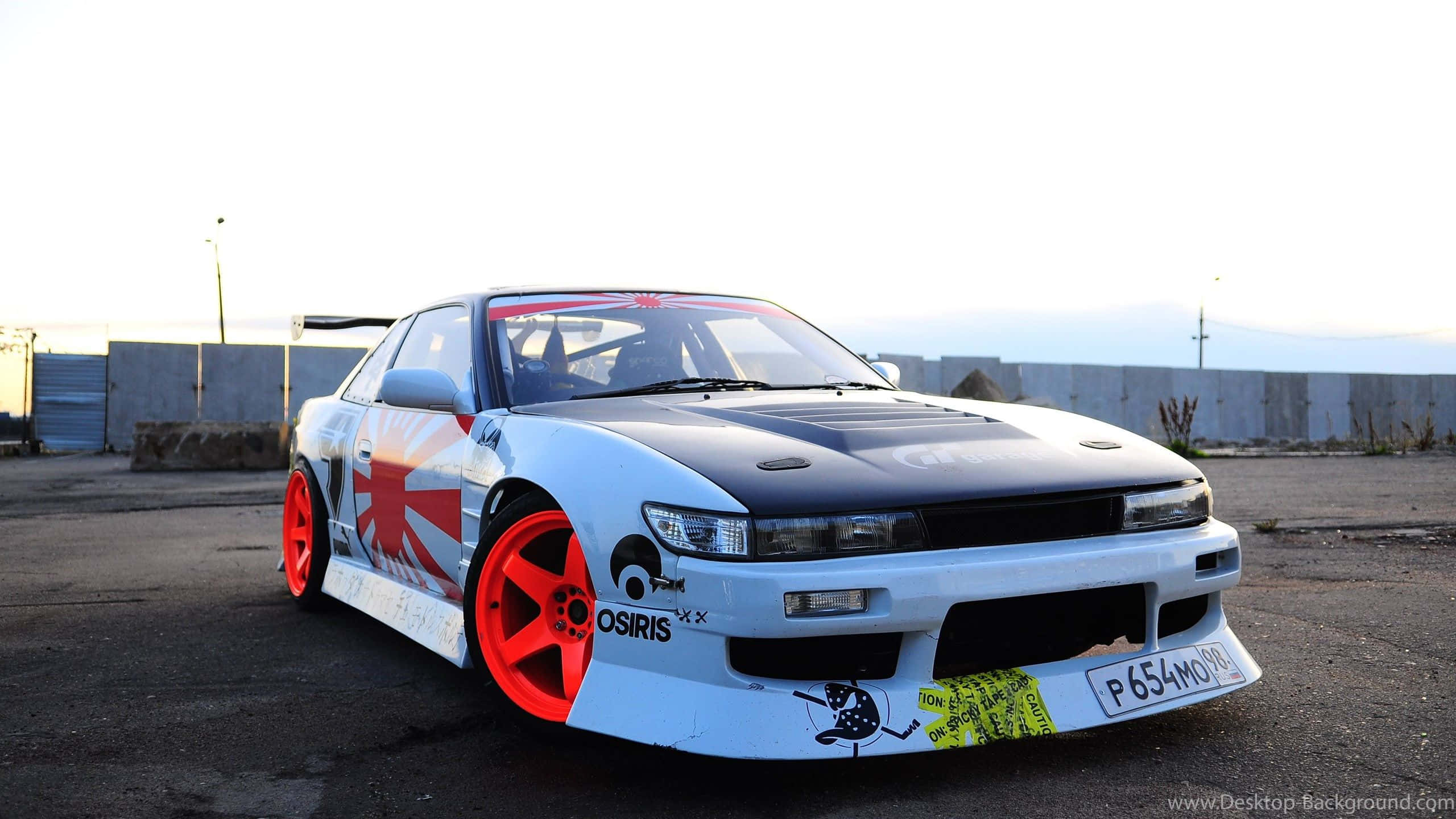 Nissan Silvia S13 桌布 壁紙 — 一輛黑白相間的漂移車，配備紅色輪圈和日本國旗塗裝，停在夕陽下的瀝青路面上。