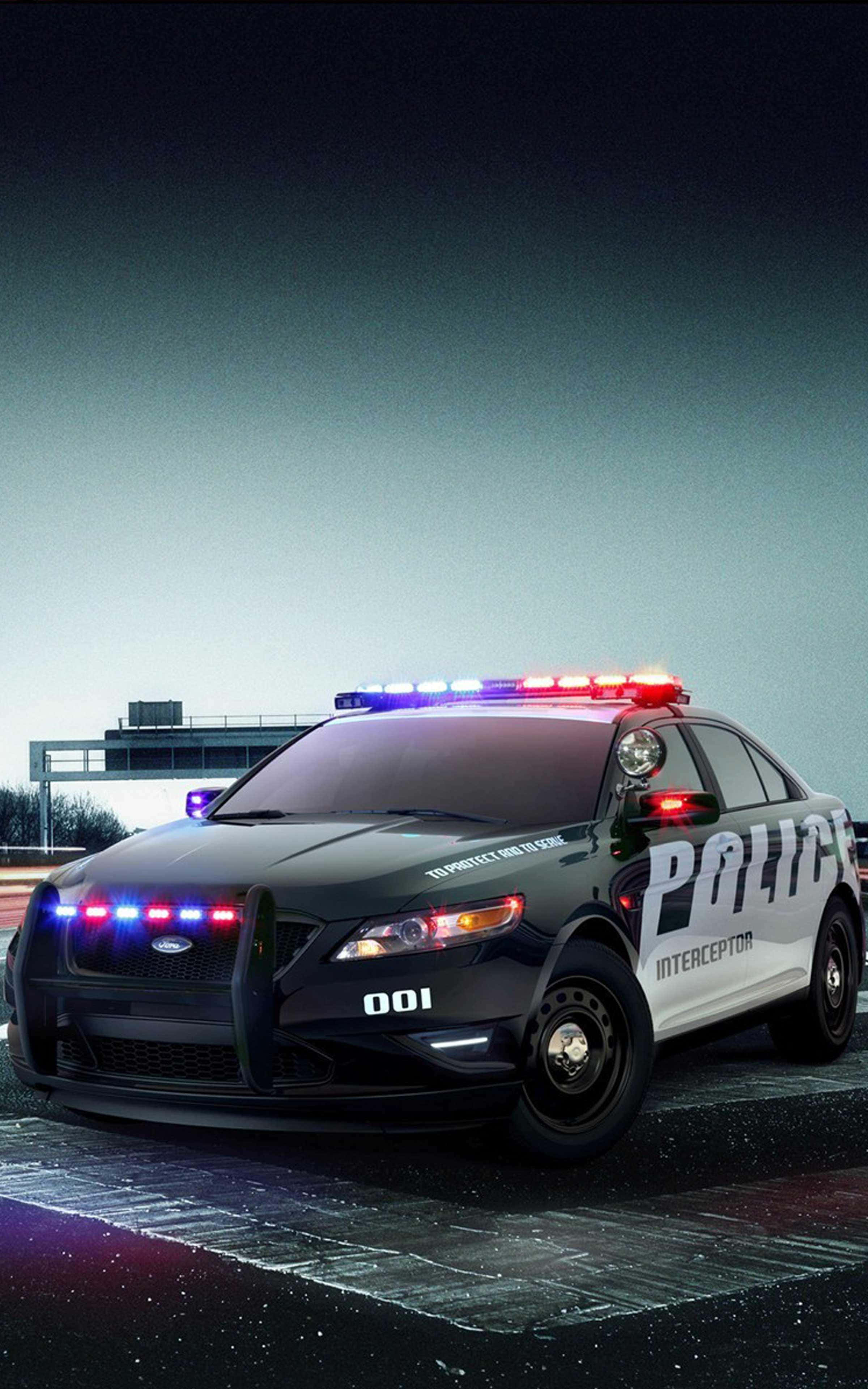 Best Cars 桌布 壁紙 — 一輛黑白警用攔截車，帶有閃爍的紅色和藍色燈光，夜間停在潮濕的道路上。