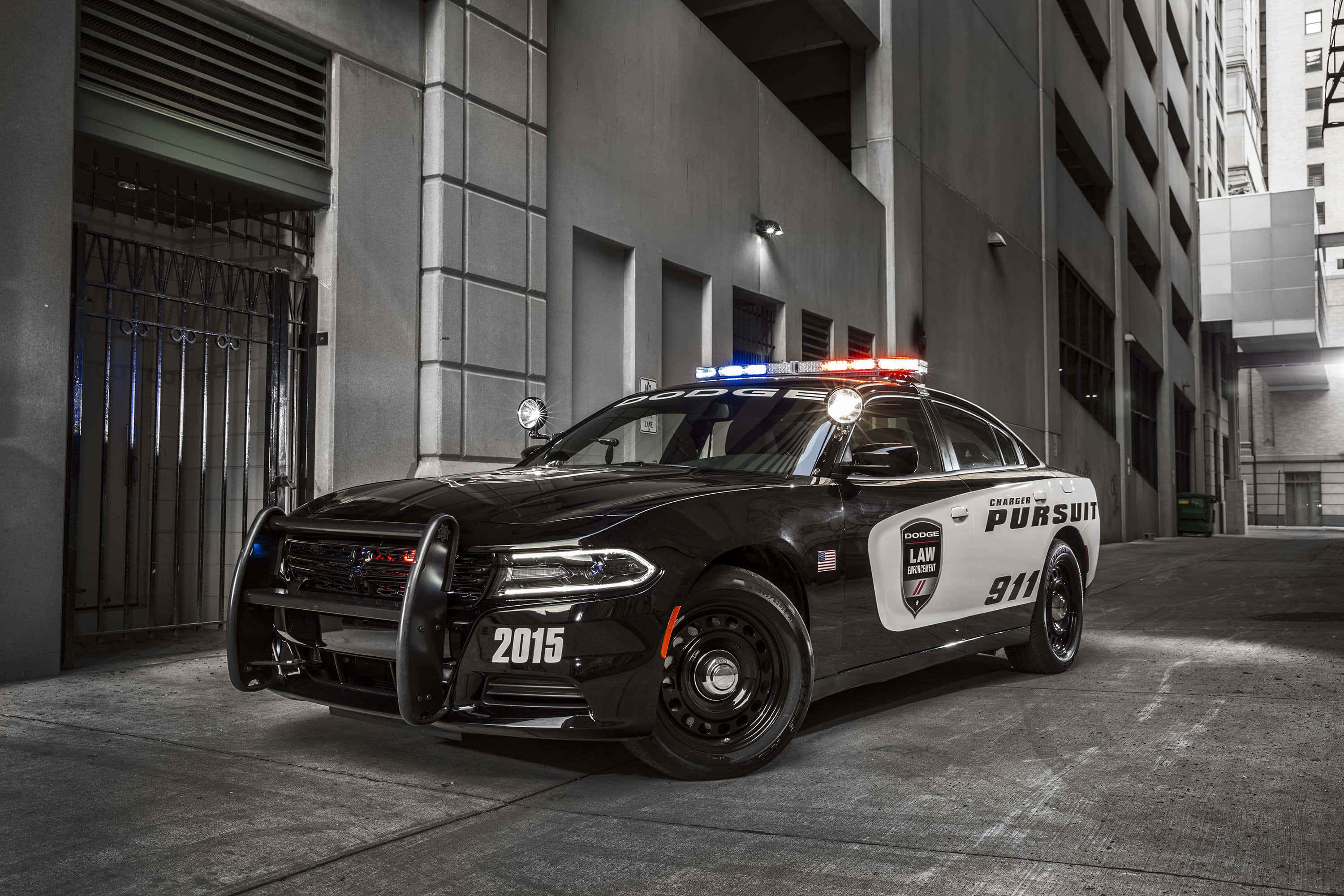 Law Enforcement 桌布 壁紙 — 一輛黑白警車閃著警燈停在高樓之間狹窄的城市小巷裡。