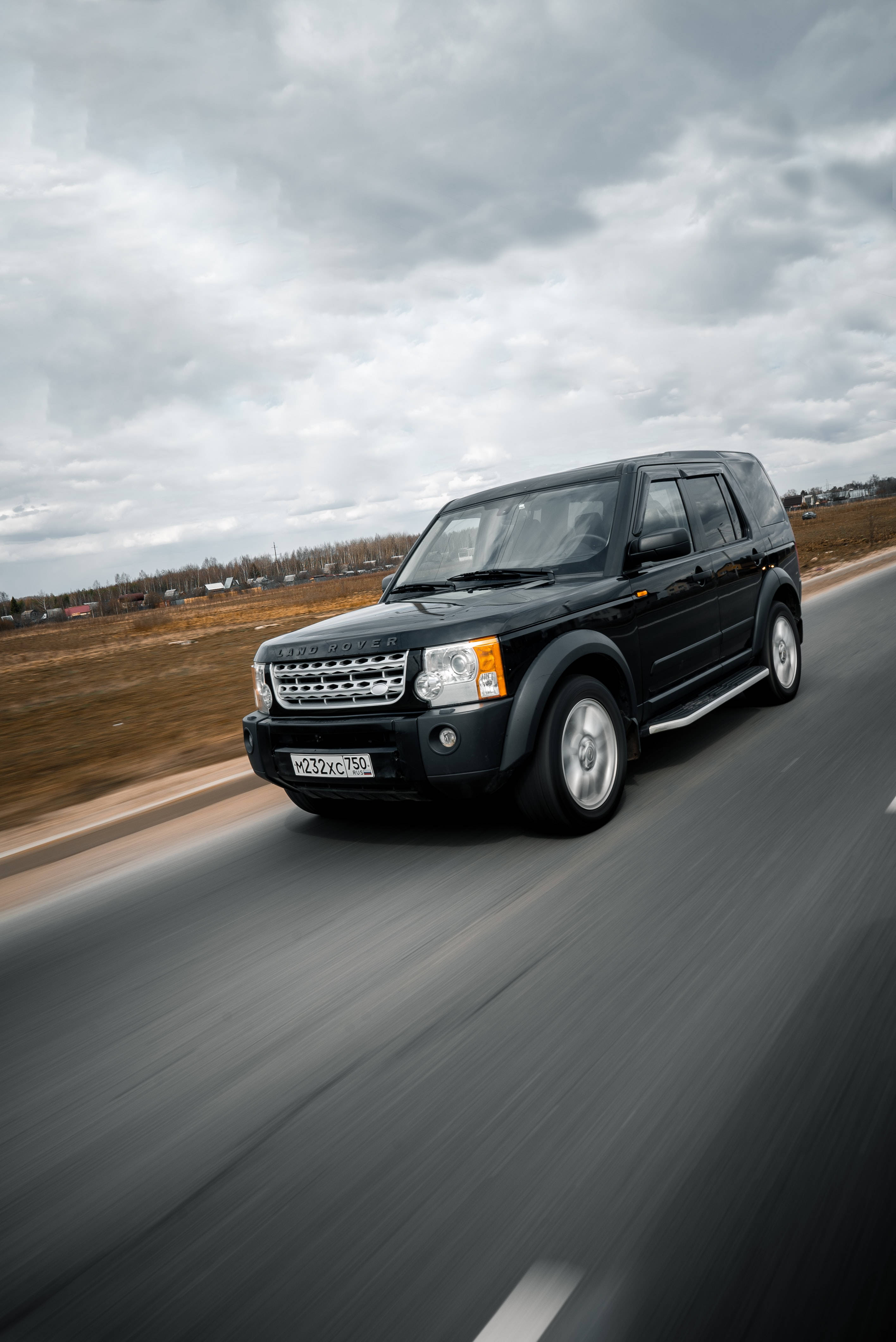 吉普 桌布 壁紙 — 一輛黑色 Land Rover Freelander 在陰沉天空下沿鄉村道路疾馳，帶有模糊動態效果。