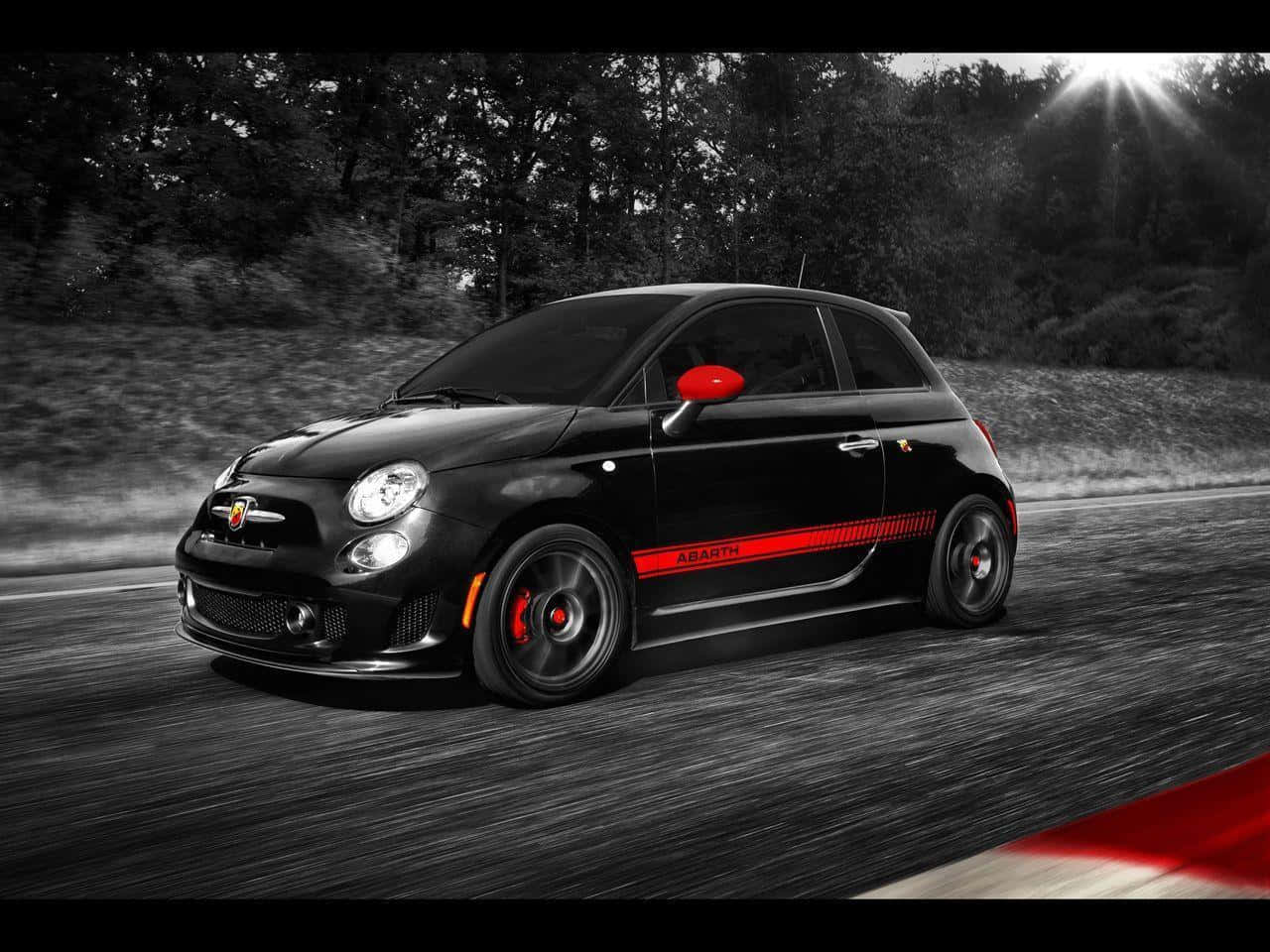 Abarth 桌布 壁紙 — 一輛黑色Fiat Abarth在陽光普照的天空下行駛，帶有動態模糊效果，鮮紅色條紋和側鏡成為亮點。
