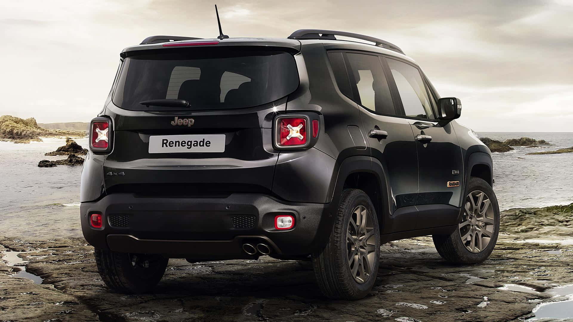 Jeep Renegade 桌布 壁紙 — 一輛黑色Jeep Renegade SUV停泊在陰天下海邊的濕岩石上。