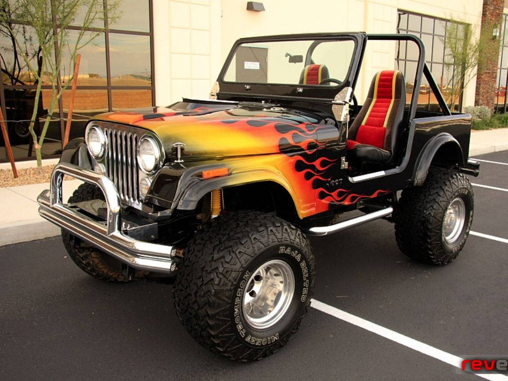 吉普 桌布 壁紙 — 一輛黑色Jeep Wrangler，帶有鮮豔的橙紅色火焰貼紙和超大輪胎，停在陽光明媚的停車場。