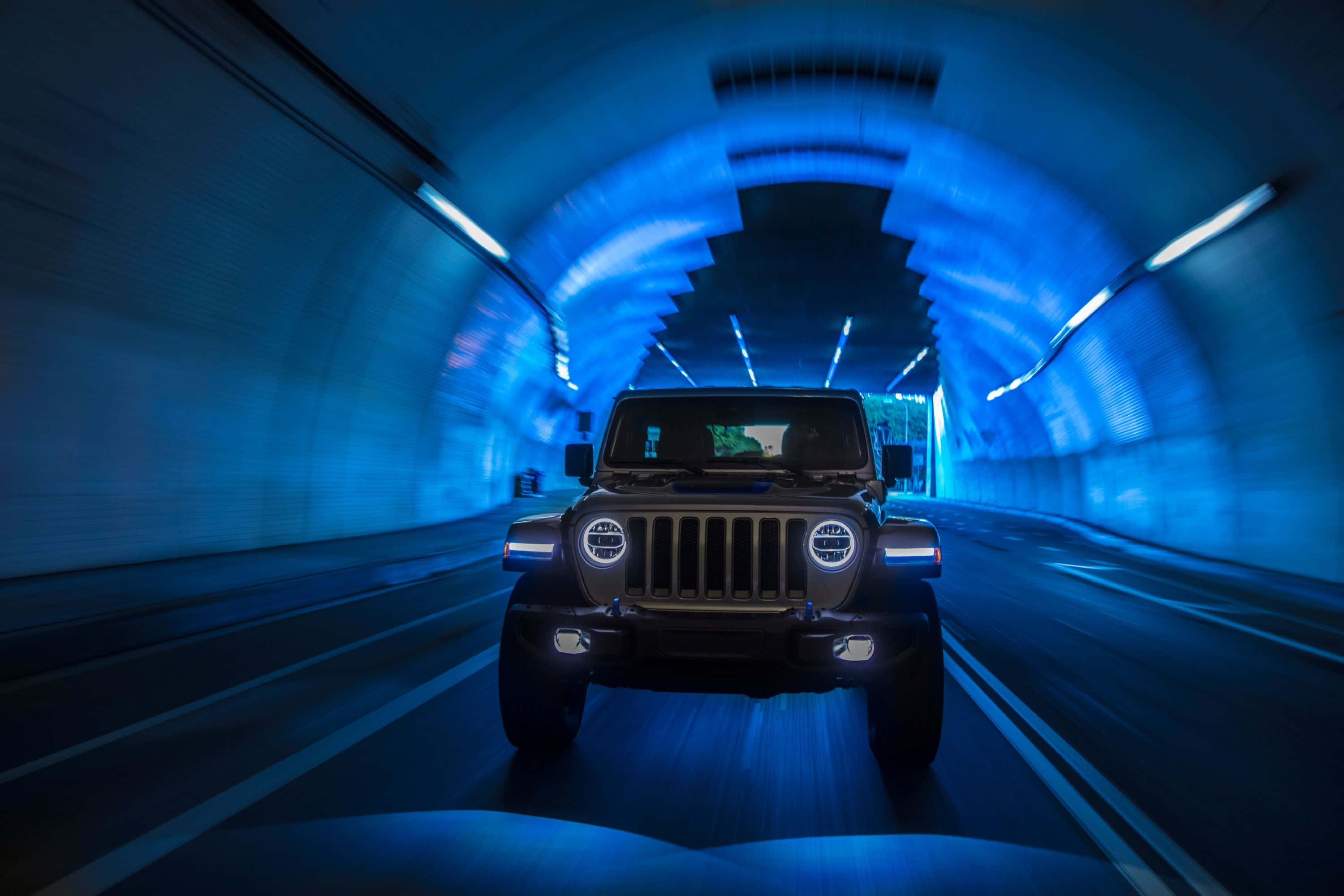 吉普 桌布 壁紙 — 一輛黑色Jeep Wrangler在藍色燈光的隧道中高速行駛，牆壁上留下動態模糊的痕跡。