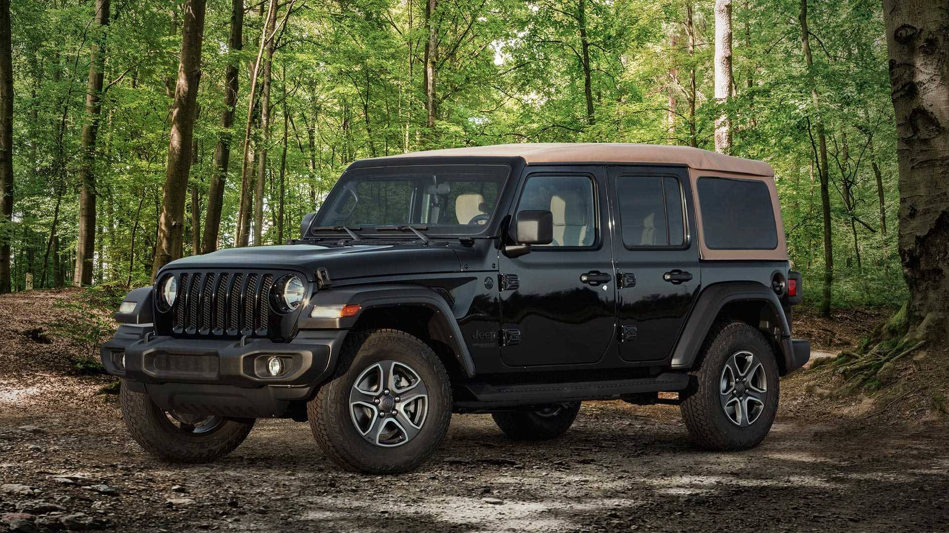 Black Jeep 桌布 壁紙 — 一輛黑色Jeep Wrangler配備棕褐色軟頂，停放在茂密綠色森林中的一條泥路上。