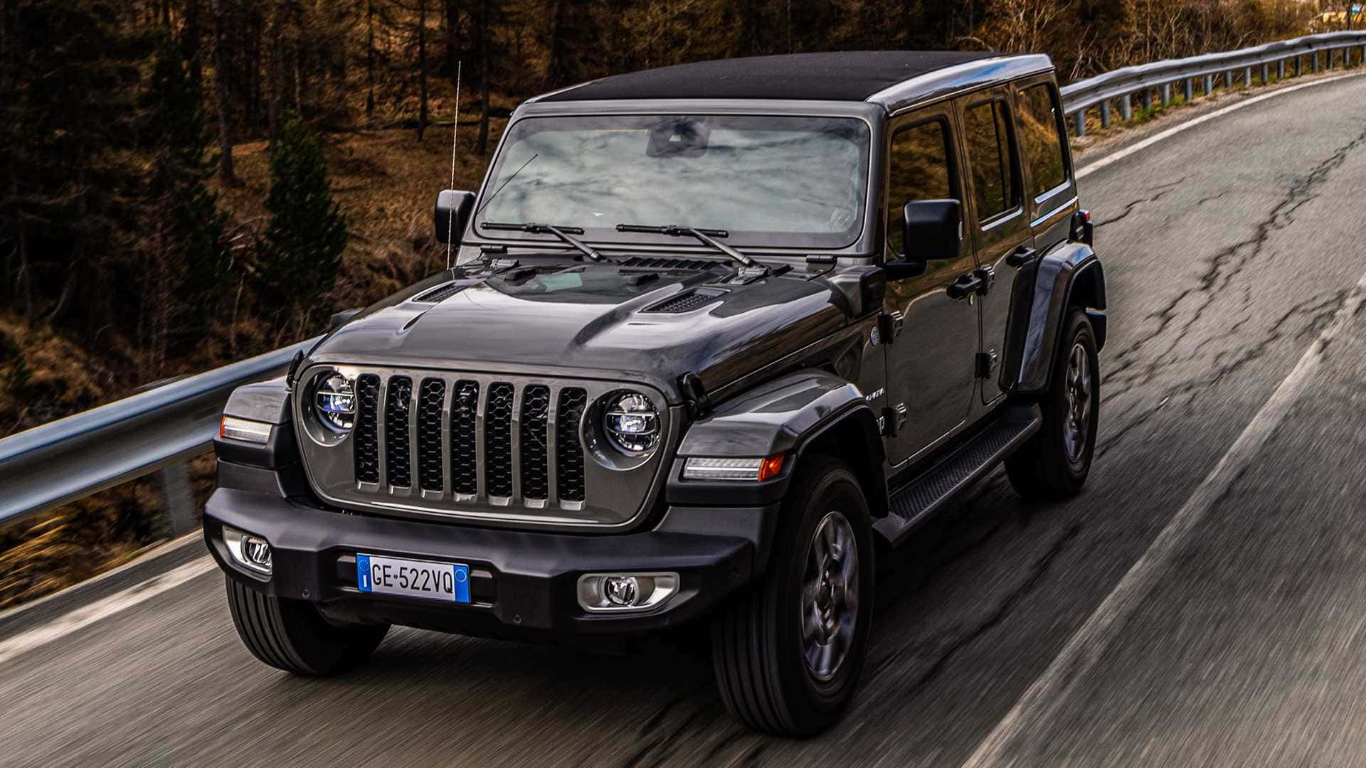 吉普 桌布 壁紙 — 一輛黑色Jeep Wrangler在蜿蜒的林間道路上行駛，帶有動態模糊和秋樹。